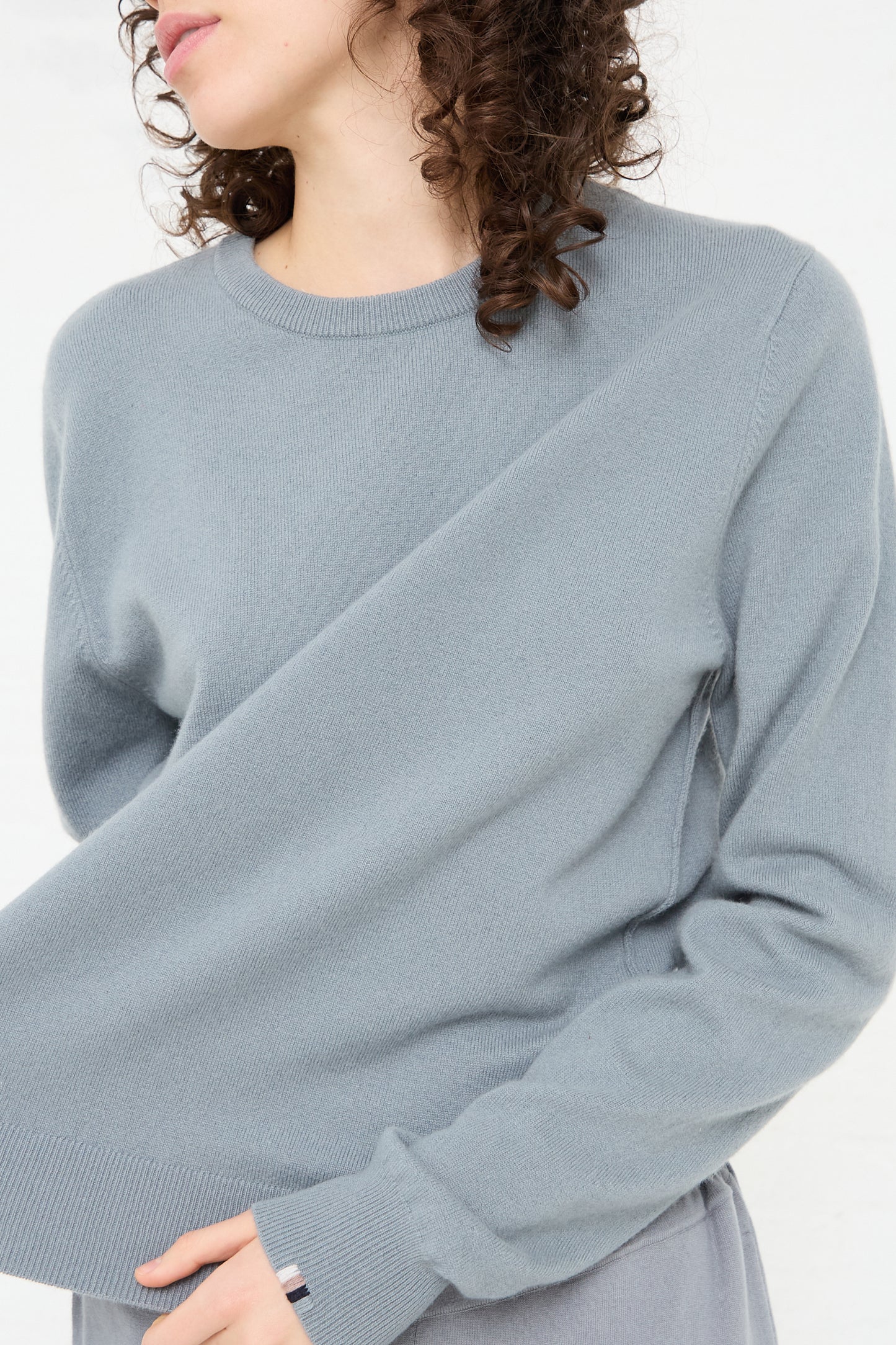 The model is wearing a No. 36 Be Classic Sweater in Sage by Extreme Cashmere.
