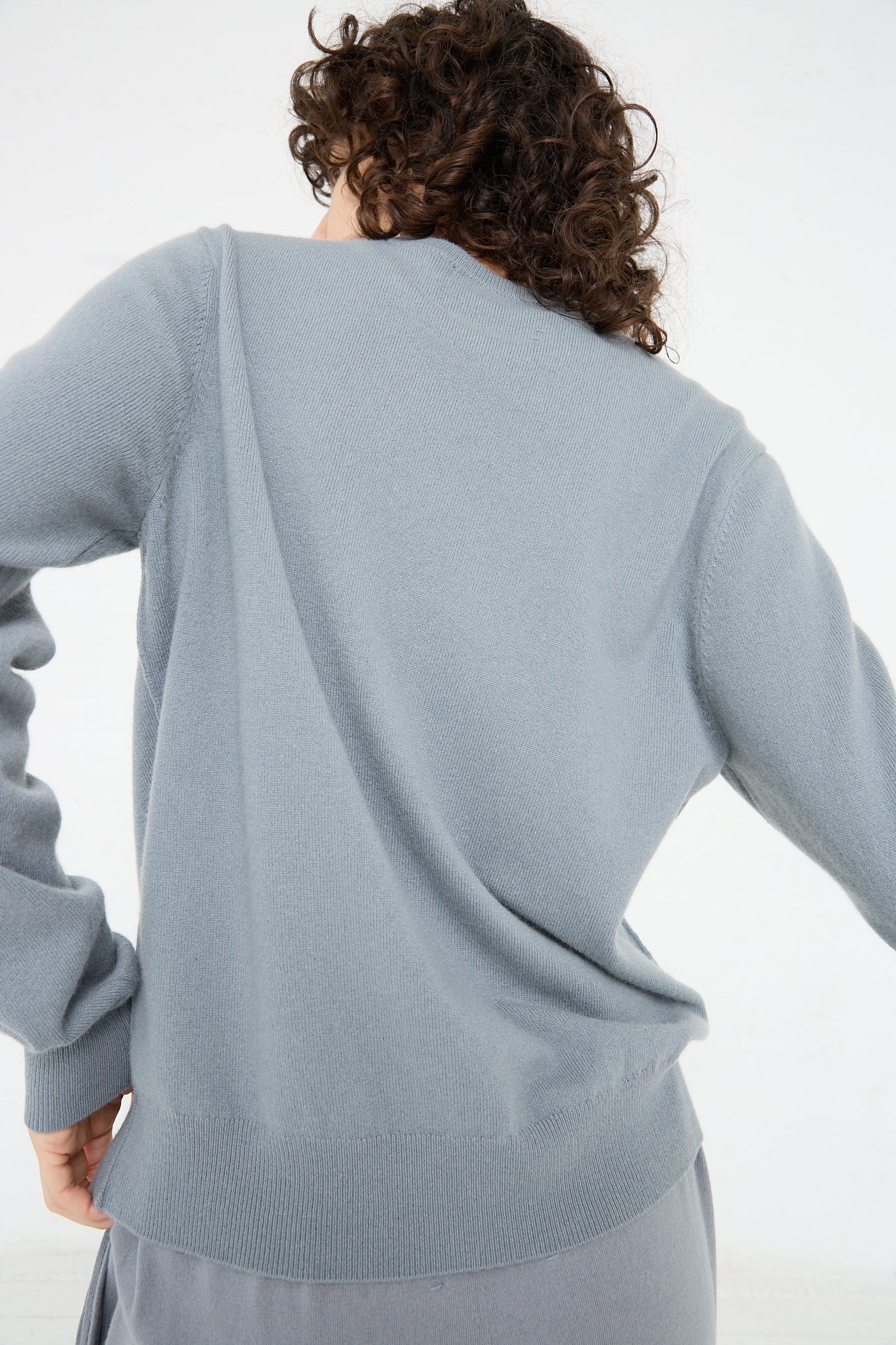 A woman in an Extreme Cashmere No. 36 Be Classic Sweater in Sage.