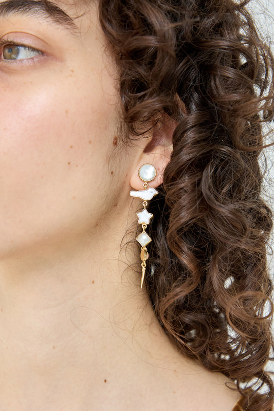 A woman wearing a pair of Grainne Morton Five Charm with Victorian Drop Earrings with a mother of pearl.