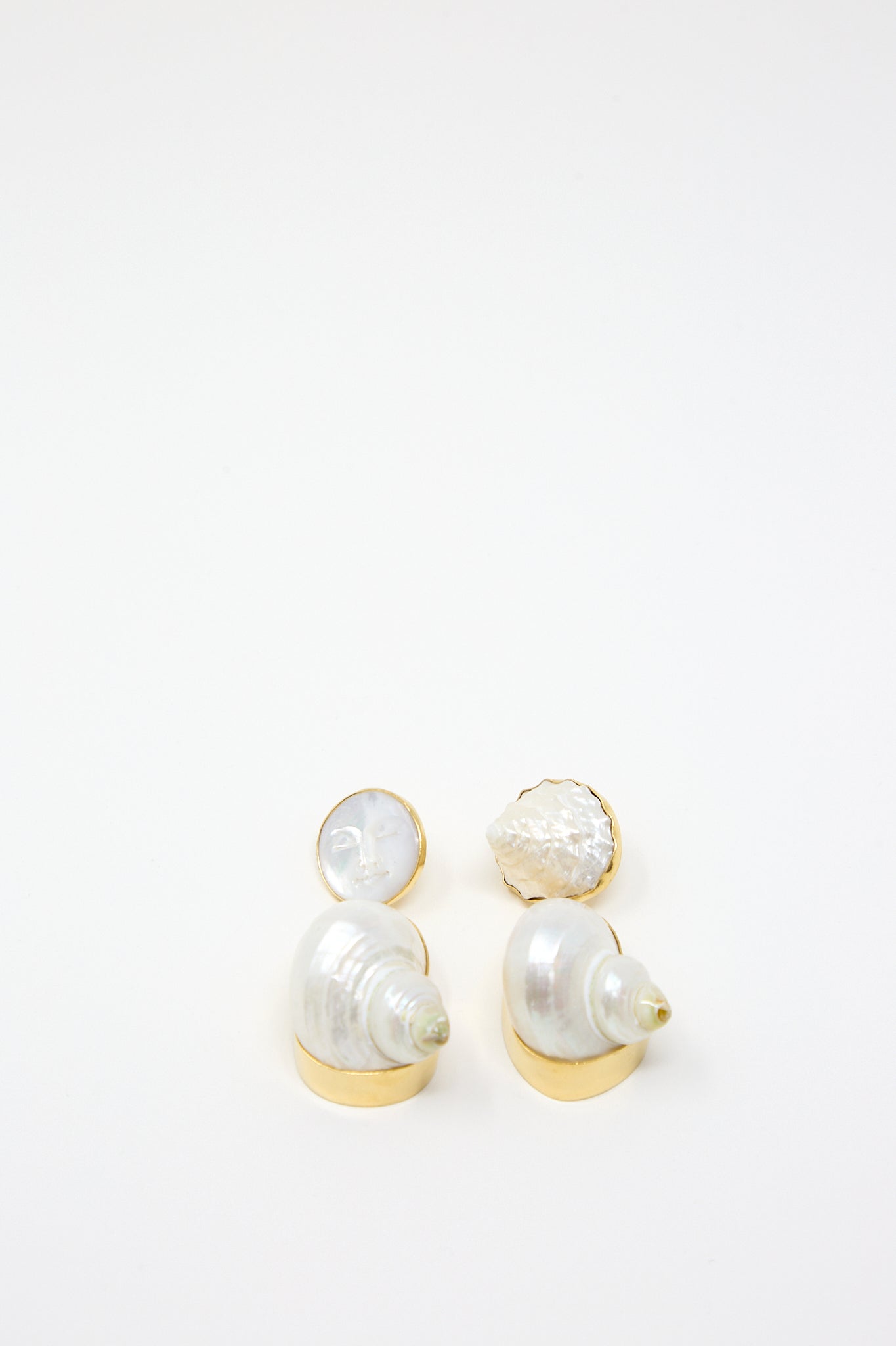 A pair of Grainne Morton Moon and Star Shell Drop Earrings with a shell and Mother of Pearl on a white surface.