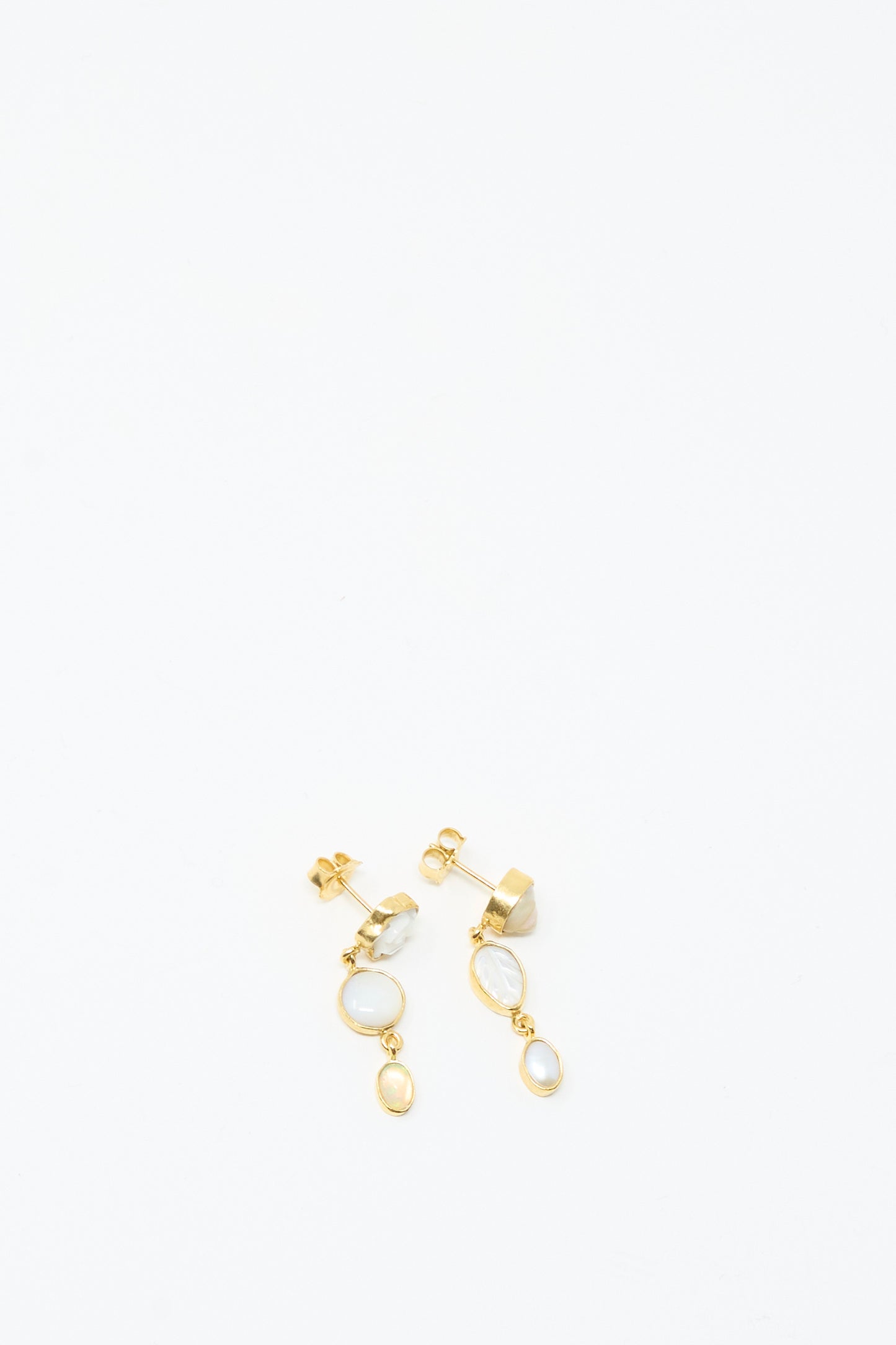 The Three Charm Moving Drop Earrings by Grainne Morton feature 18K gold plating, white oval stones, and small circular accents, beautifully displayed on a white background.