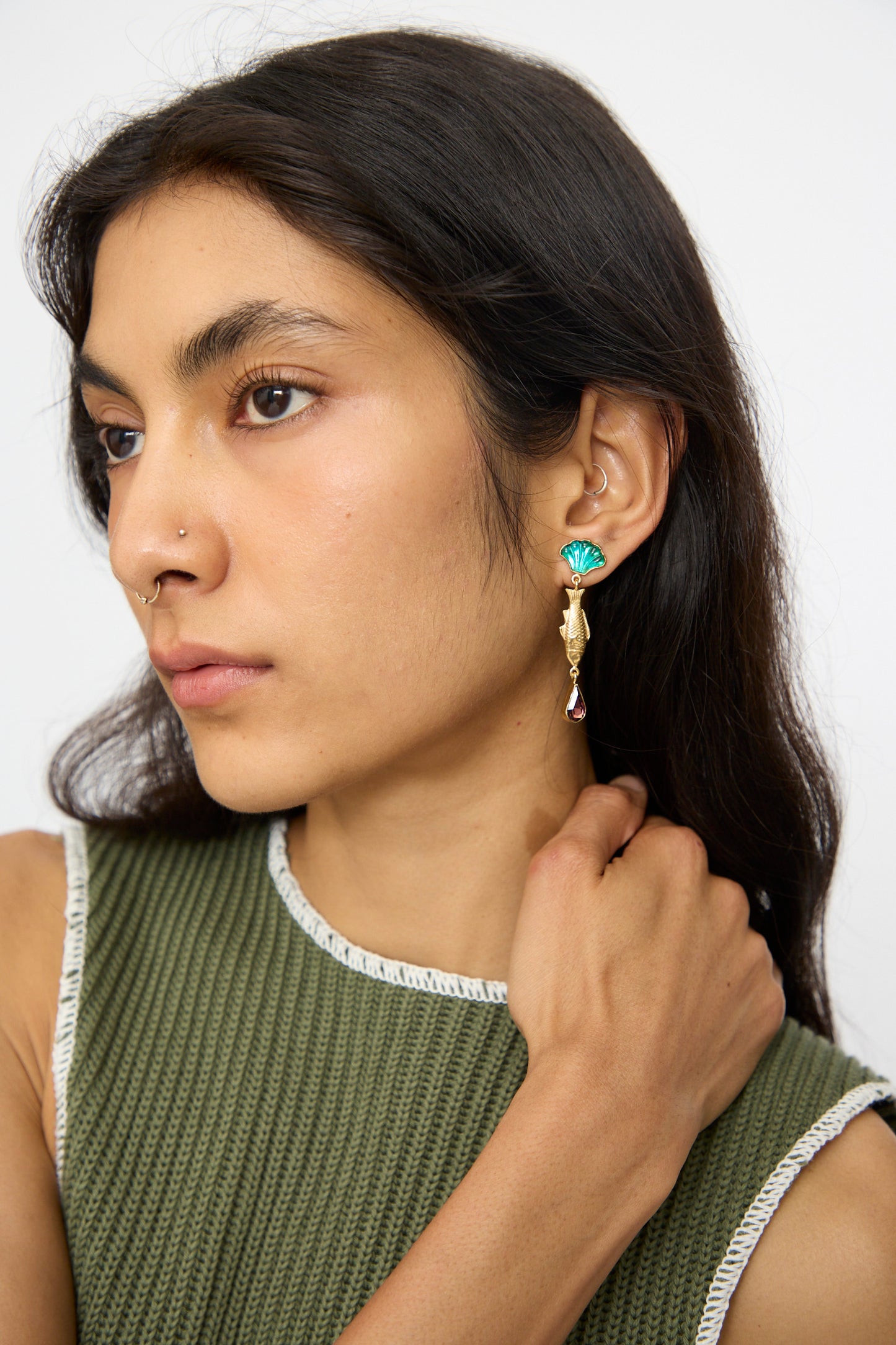 Woman with long dark hair wearing a green sleeveless top, 18K gold plated silver nose ring, and Grainne Morton Fish and Vintage Cabochon Drop Earrings, handmade in Edinburgh, looking to the side with her hand touching her neck.