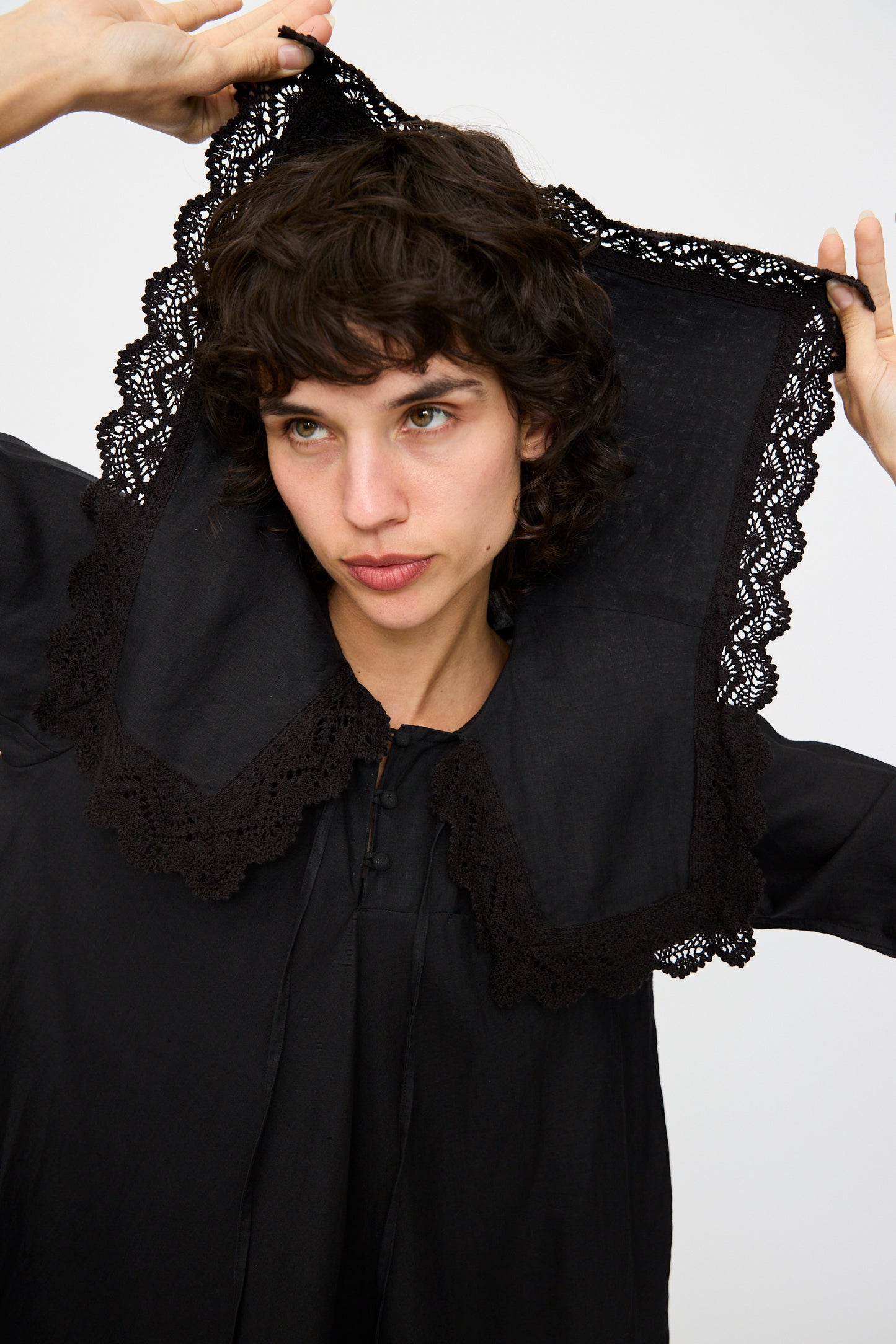 A person showcases the Hallelujah Robe Religieuse col carré in Black with a sophisticated A-line silhouette and a large lace-trimmed collar, against a black background.