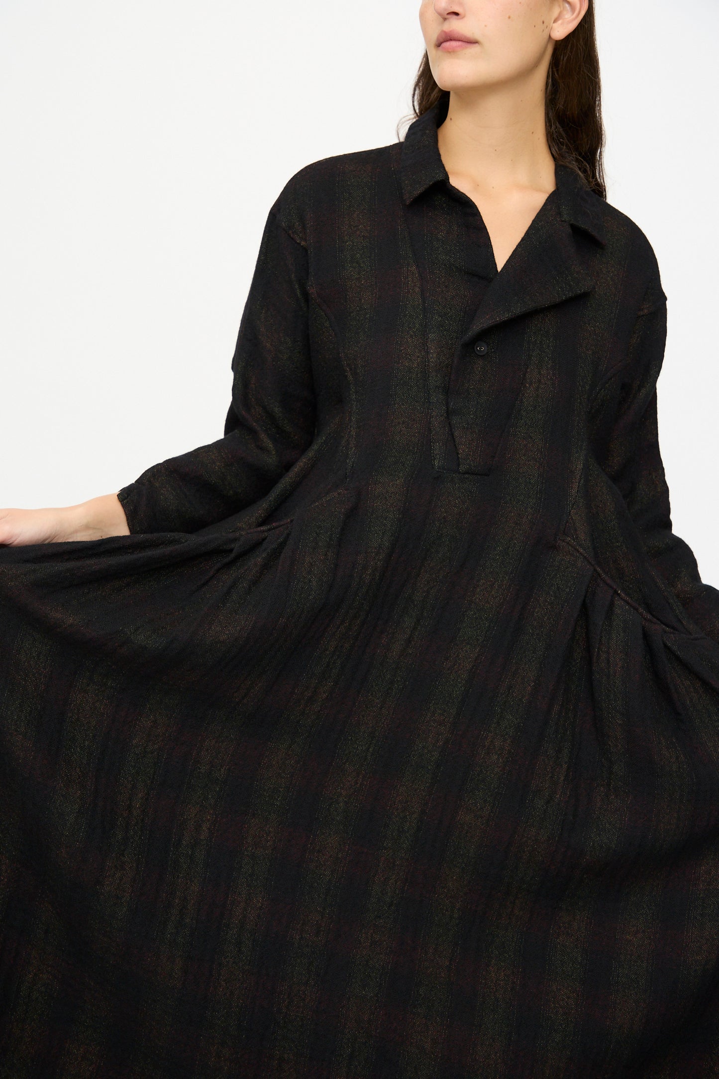 A woman models the Hallelujah Wool Cotton Robe de Berger in Black Mix, made in Japan, holding the sides to showcase its wide silhouette and checkered wool-cotton blend fabric.