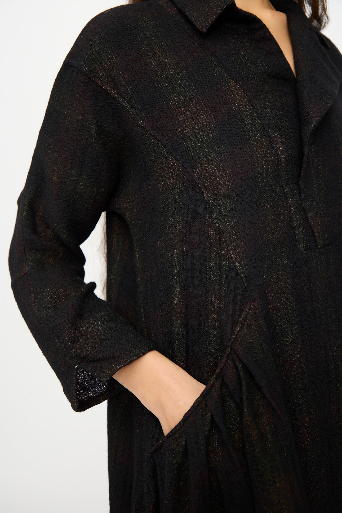 A person wearing the Hallelujah Wool Cotton Robe de Berger in Black Mix, a long-sleeved, collared dress with a front pocket, shown from shoulder to hip.