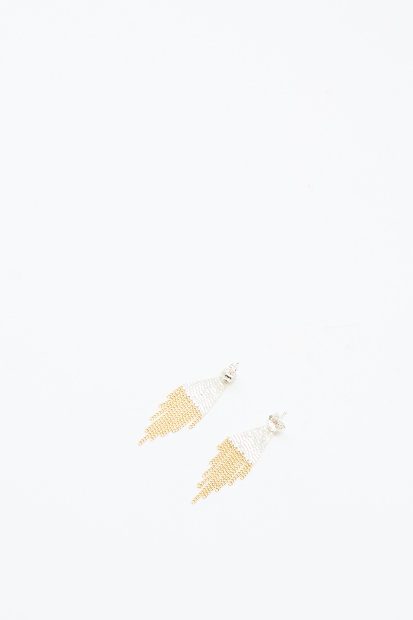 The Hannah Keefe Lil Triangle Studs in Brass and Silver are displayed on a plain white background. These handmade, earrings feature brass and silver beads with a unique triangular design.