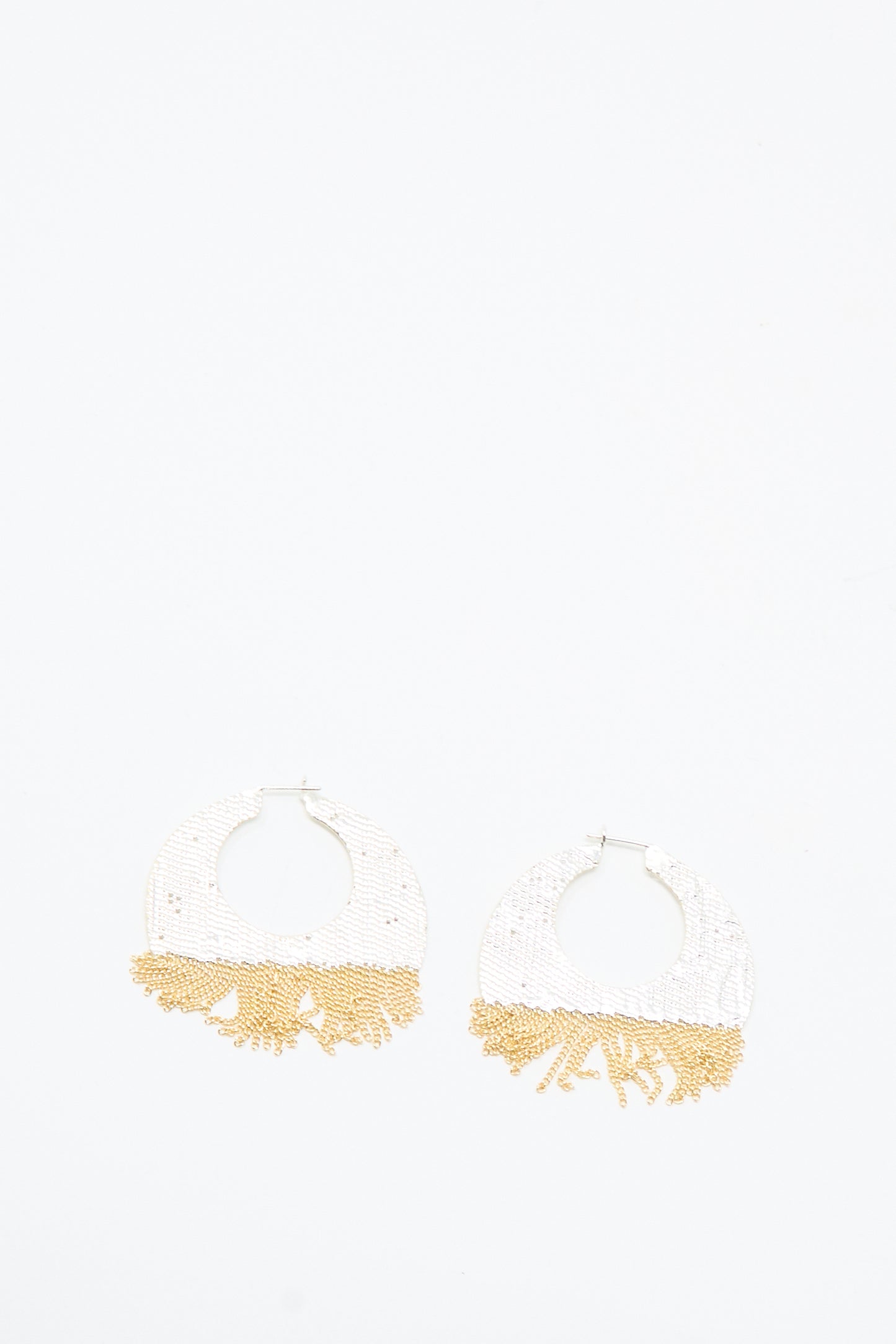 The True Hoops in Brass and Silver by Hannah Keefe are handmade earrings with round white beads on top and gold fringe beading on the bottom, shown against a white background.