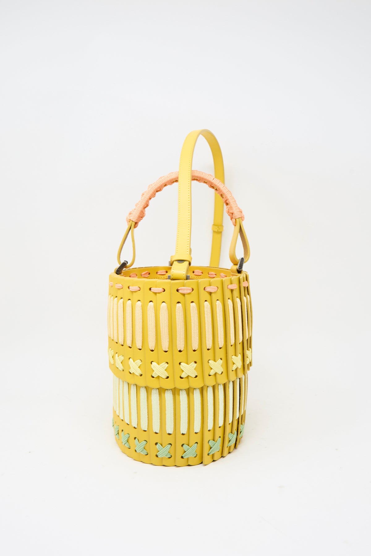 Hatori Leather Bucket 80 Artist Edition with Holly Coulis in yellow: a cylindrical vegetable-tanned leather bucket bag with woven panels and a pale pink braided handle.