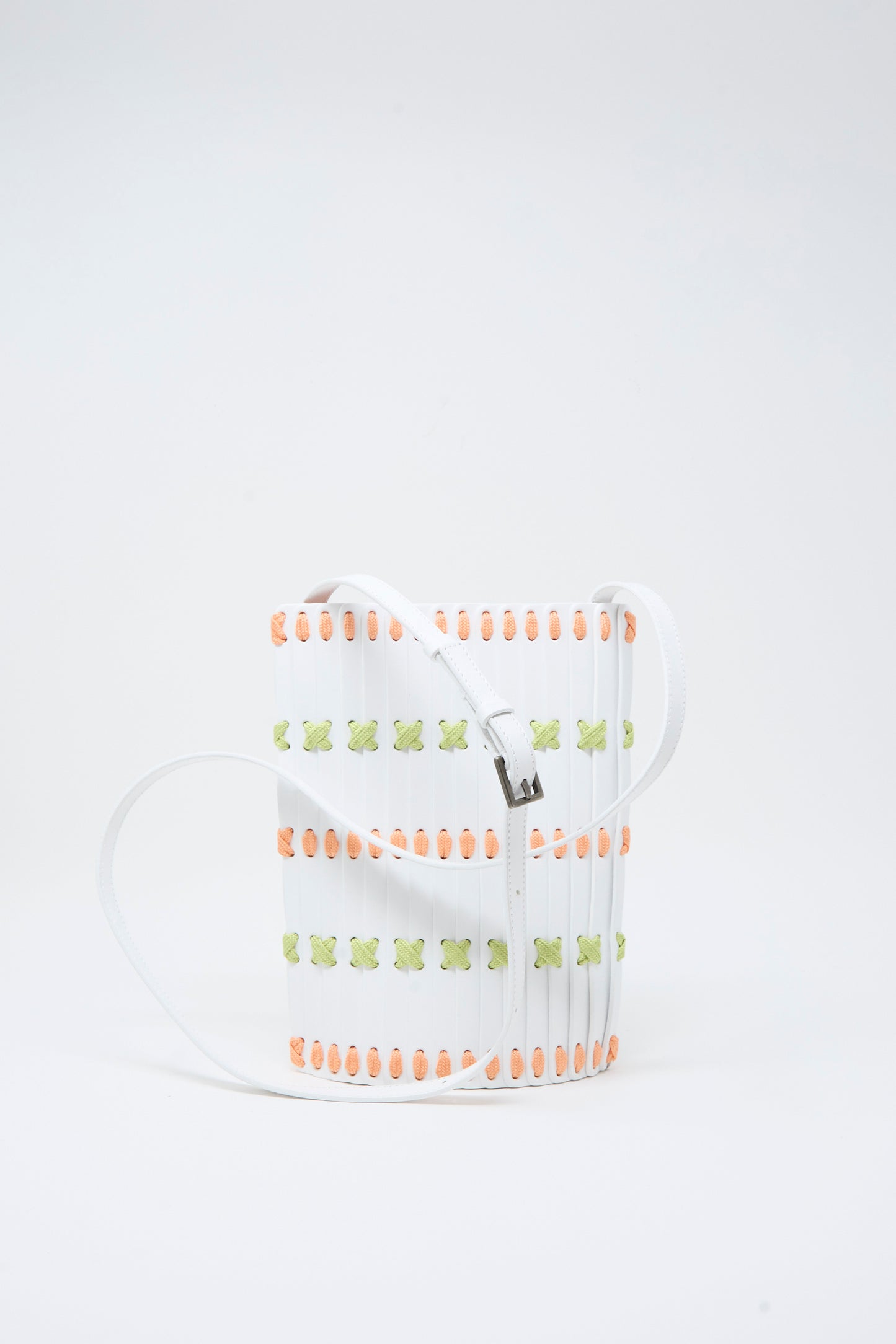 A handcrafted rectangular white Leather Crossbody 30 by Hatori, featuring multi-color lacing in orange and green accents, detailed with vertical slats and a long white strap, set against a plain white background.