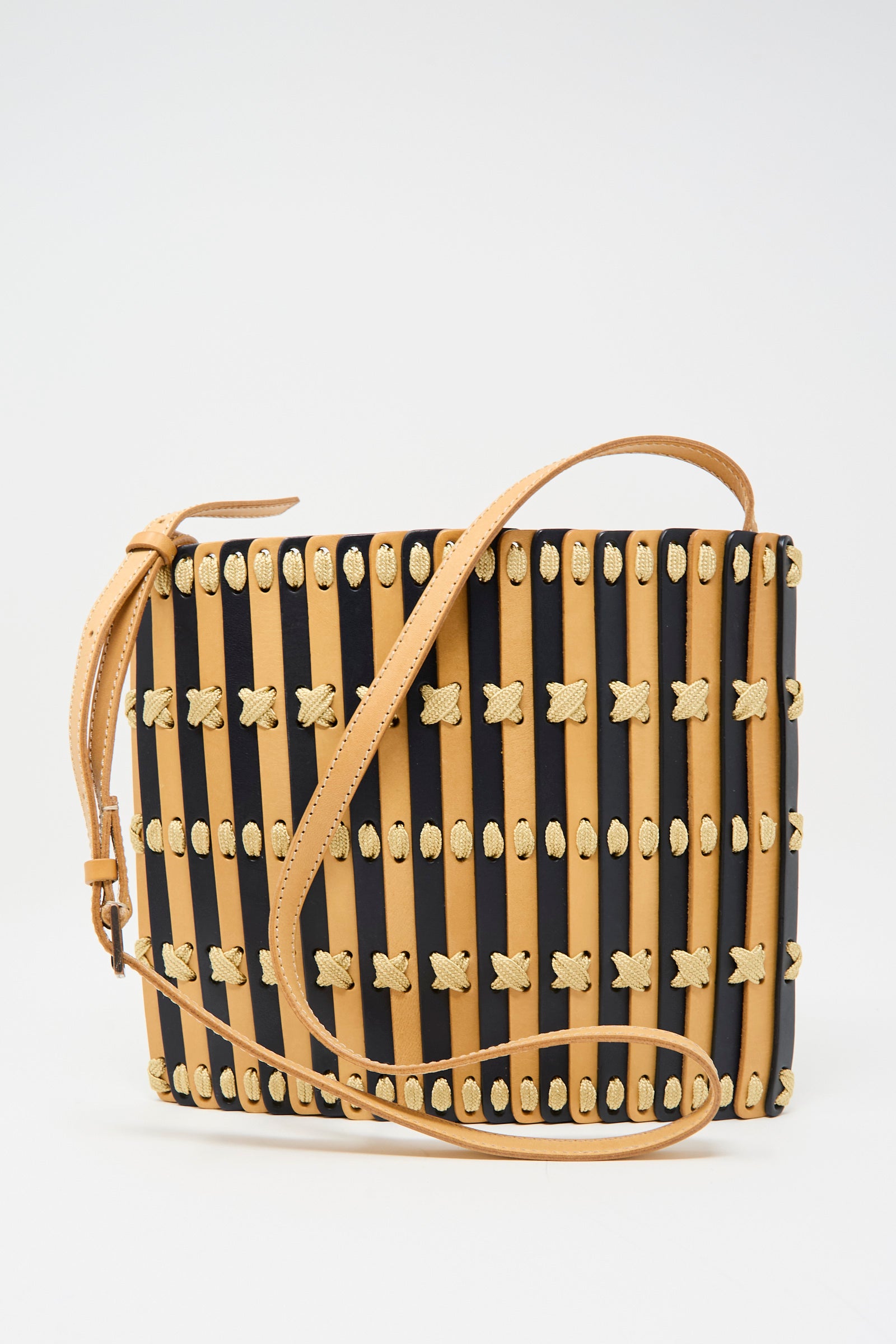 The Hatori Leather Crossbody 48 in Midnight Blue with Ecru Lace features a rectangular design, adjustable tan leather strap, alternating tan and navy stripes, and is accented with woven cream-colored knots.