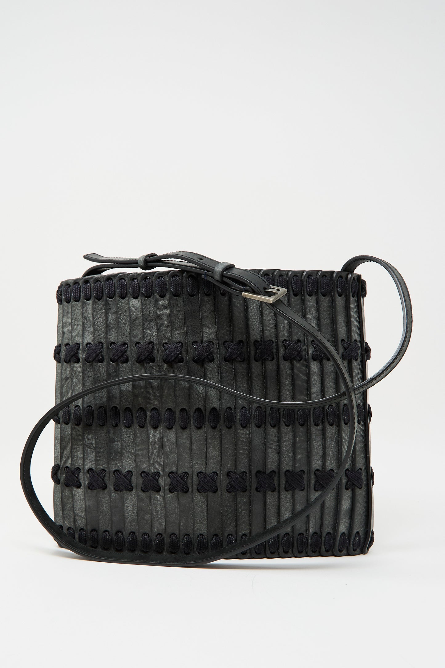 The Hatori Leather Crossbody 48 Bag in waxed coated black with indigo lace features a handcrafted rectangular design, decorative stitching, vertical strips, and an adjustable shoulder strap, shown against a plain background.