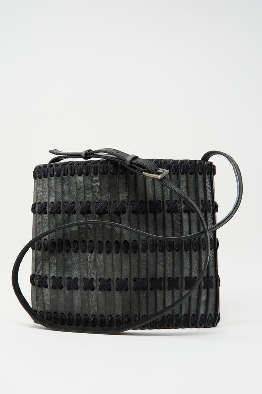 The Hatori Leather Crossbody 48 Bag in waxed coated black with indigo lace features a handcrafted rectangular design, decorative stitching, vertical strips, and an adjustable shoulder strap, shown against a plain background.