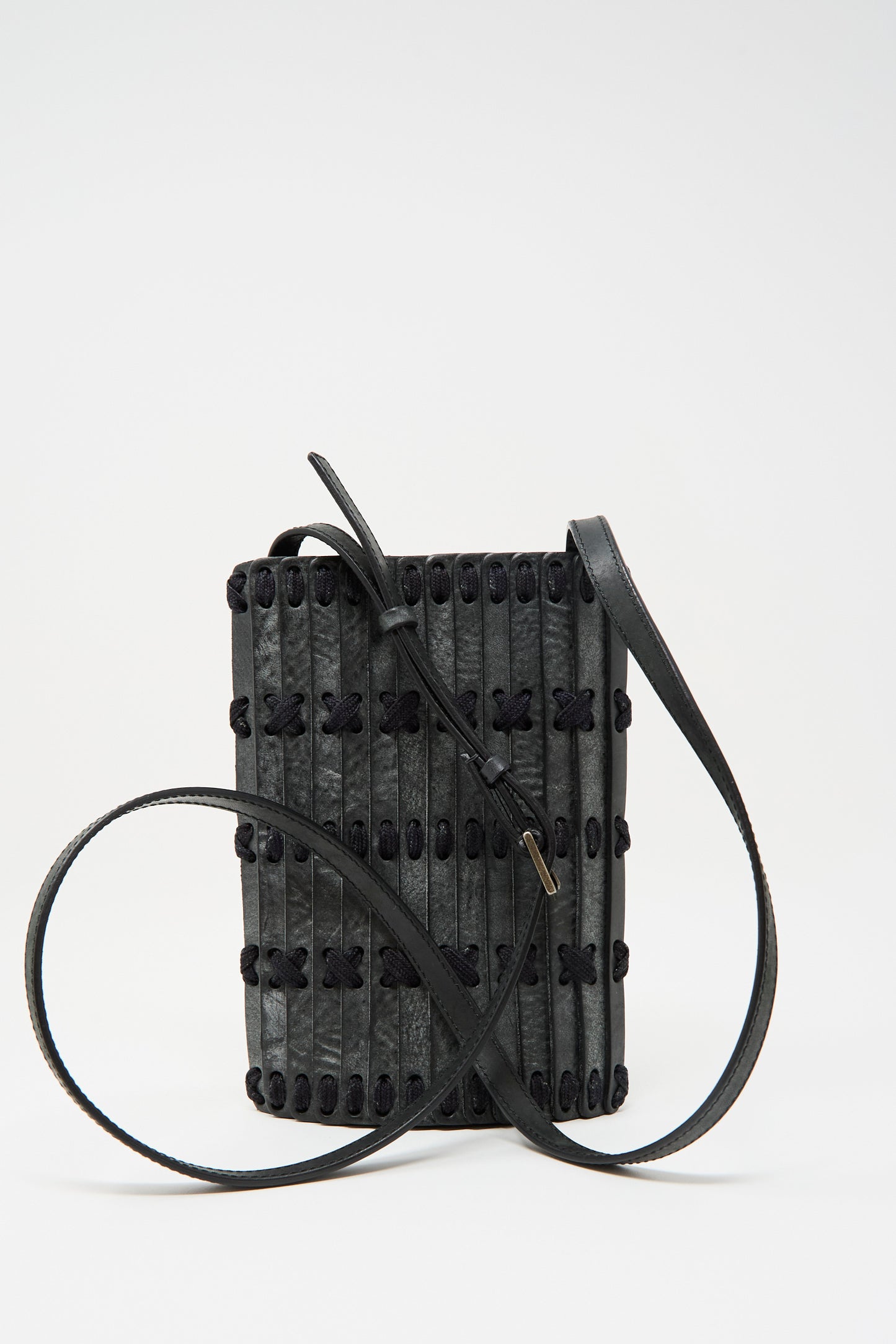 The Hatori Leather Phone 26 Bag features waxed coated black leather with indigo lace, a textured vertical stripe design, decorative black stitching, and a long adjustable strap. Handcrafted in Tokyo from premium vegetable tanned leather.