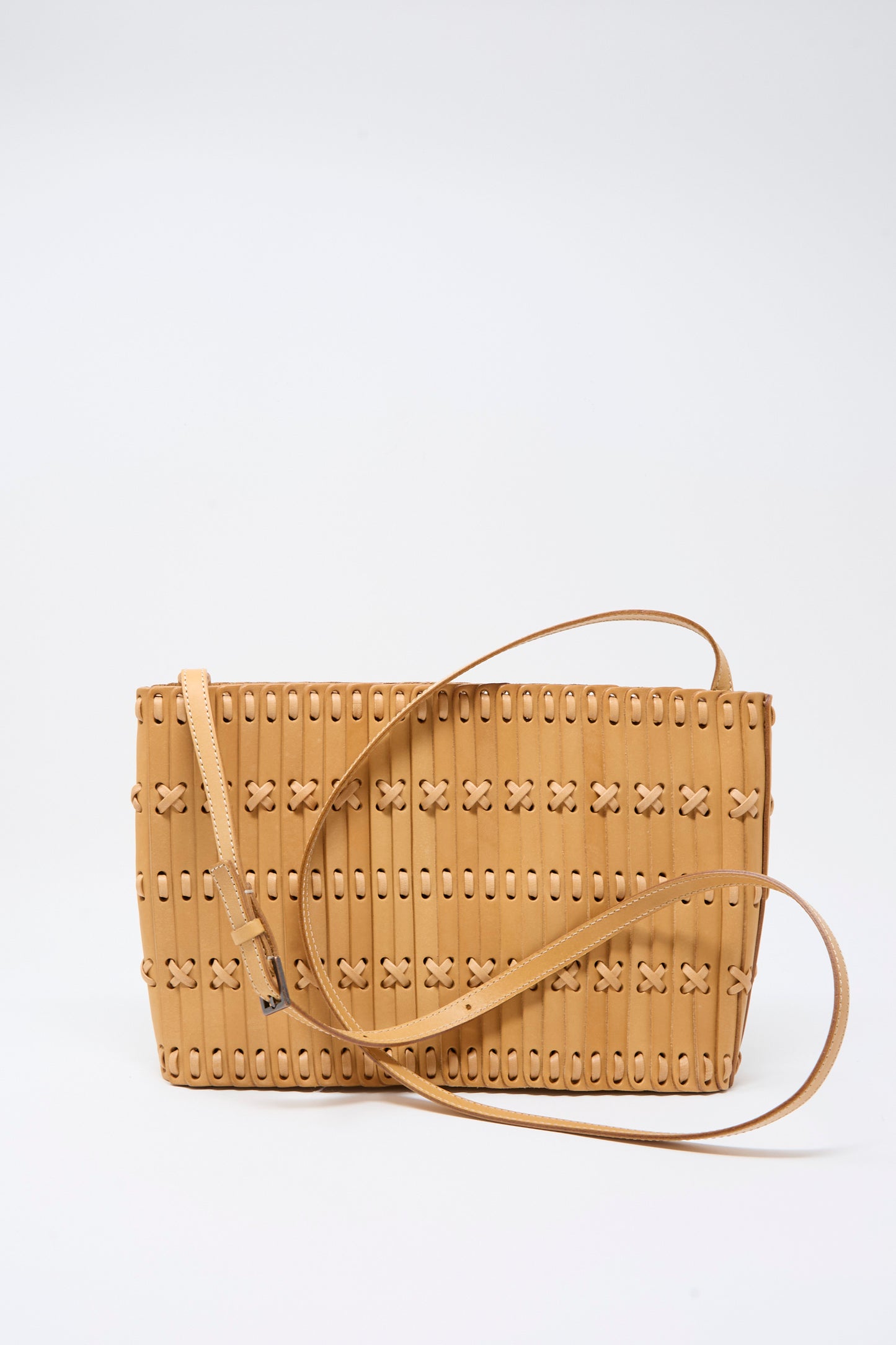 The Hatori Leather Shoulder 60 Bag in Natural with Tan Lacing is a handcrafted crossbody, made from premium vegetable-tanned leather and featuring a long strap. Designed with vertical slits and small X-shaped laced details, this unique shoulder bag is showcased against a plain white background.