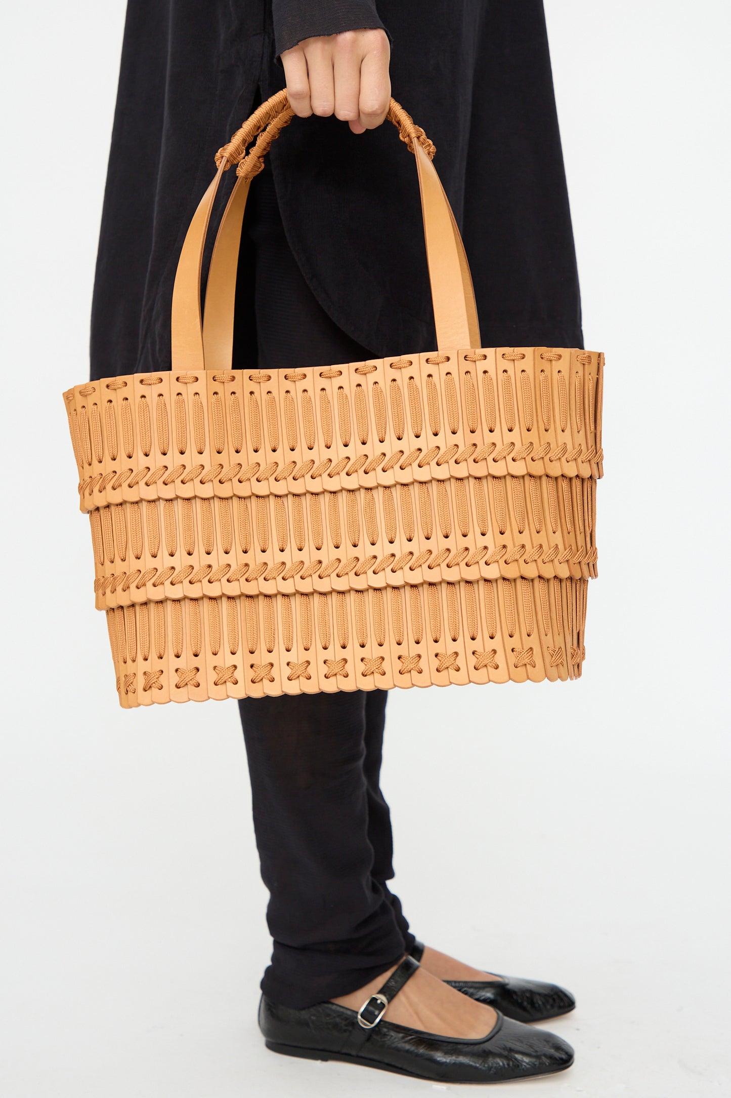 A person holds the Hatori Leather Tote 198 in Natural with Natural Lace, styled with black pants, black flats, and a dark top against a plain background.