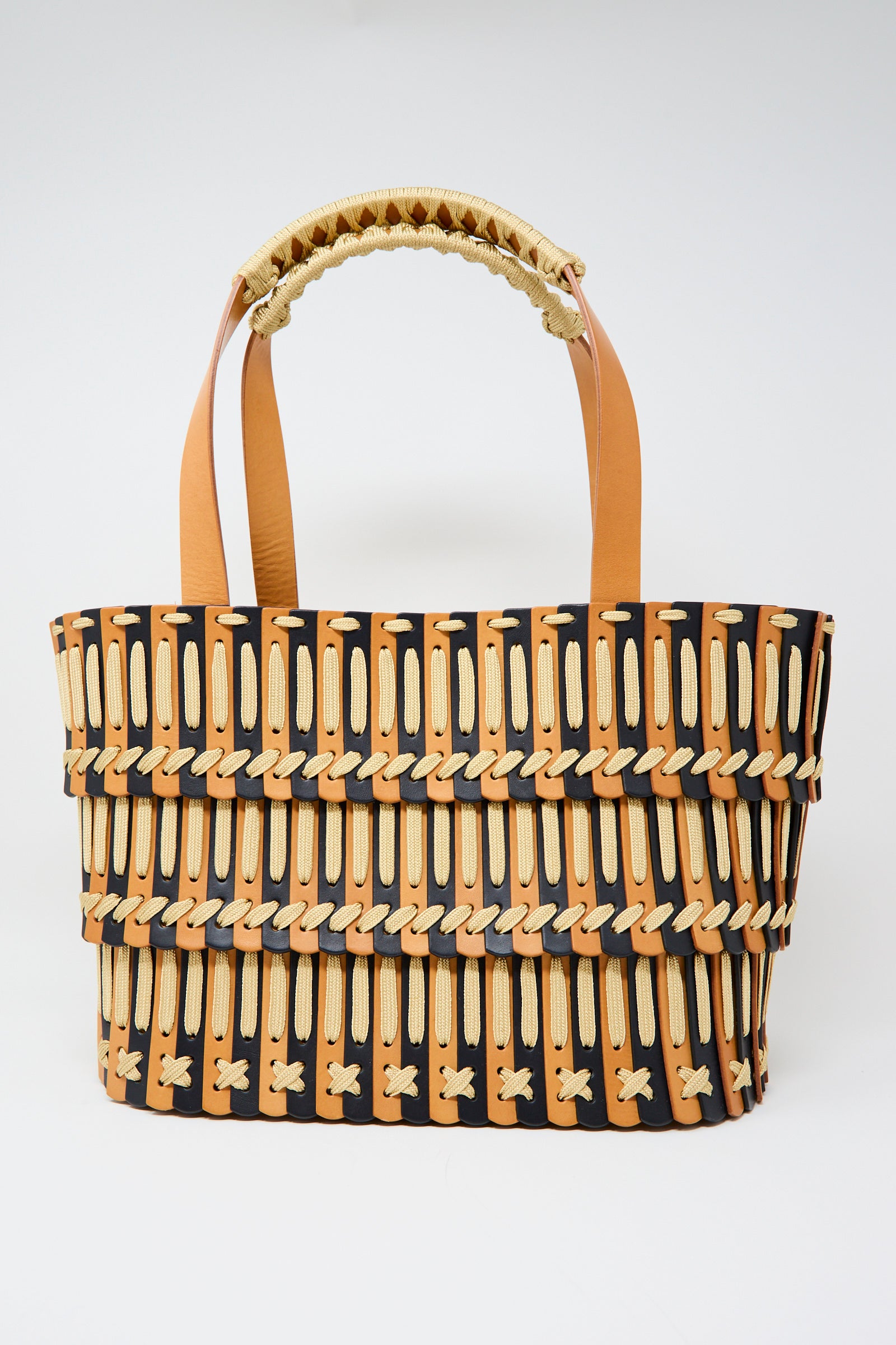 The Hatori Leather Tote 198 Bag features natural leather handles and a geometric midnight blue, ecru lace, and black pattern, showcased against a plain white background.