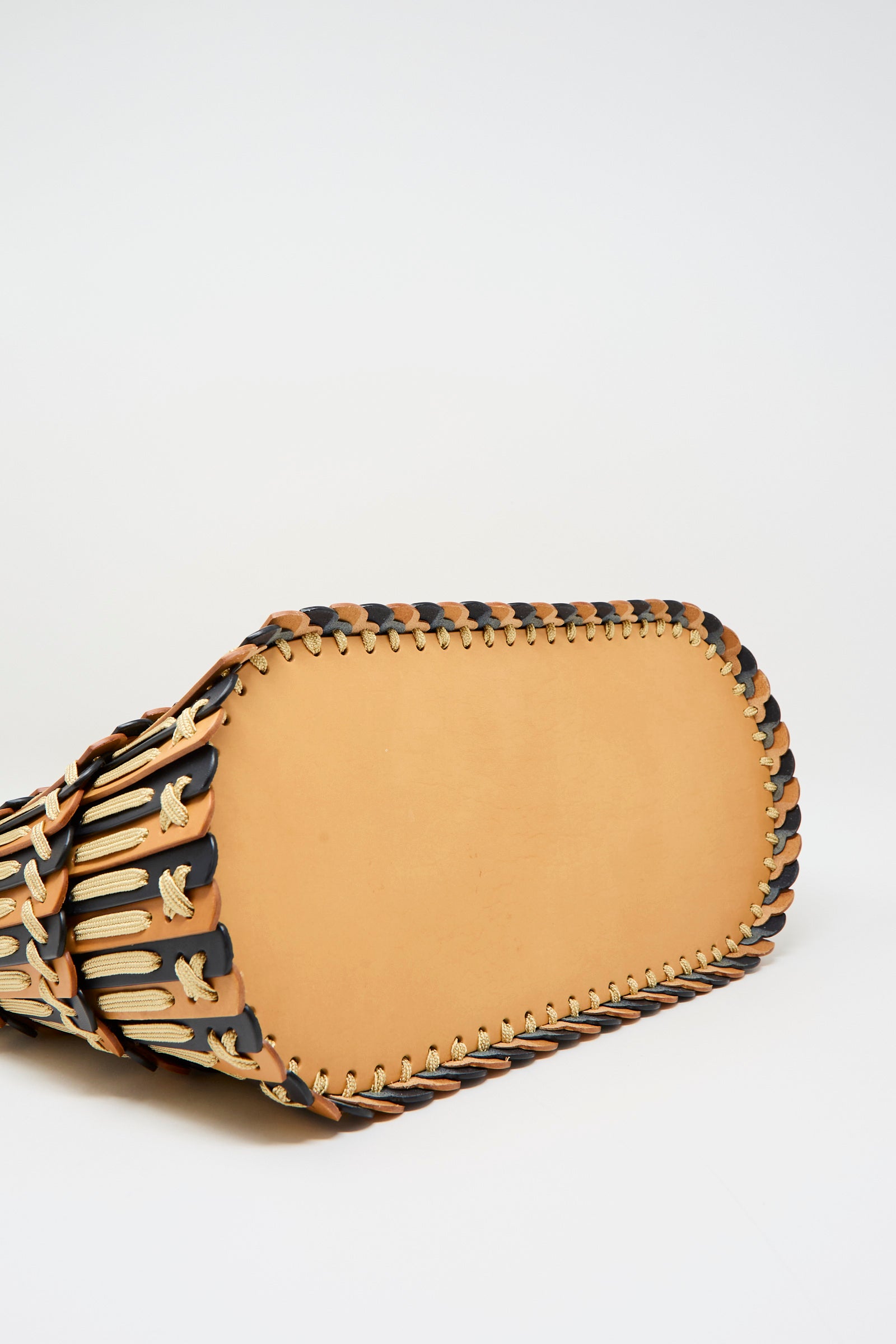 Close-up of the bottom of the Hatori Leather Tote 198 Bag in Natural and Midnight Blue with Ecru Lace, showing handcrafted woven leather strips in a decorative stitched pattern.