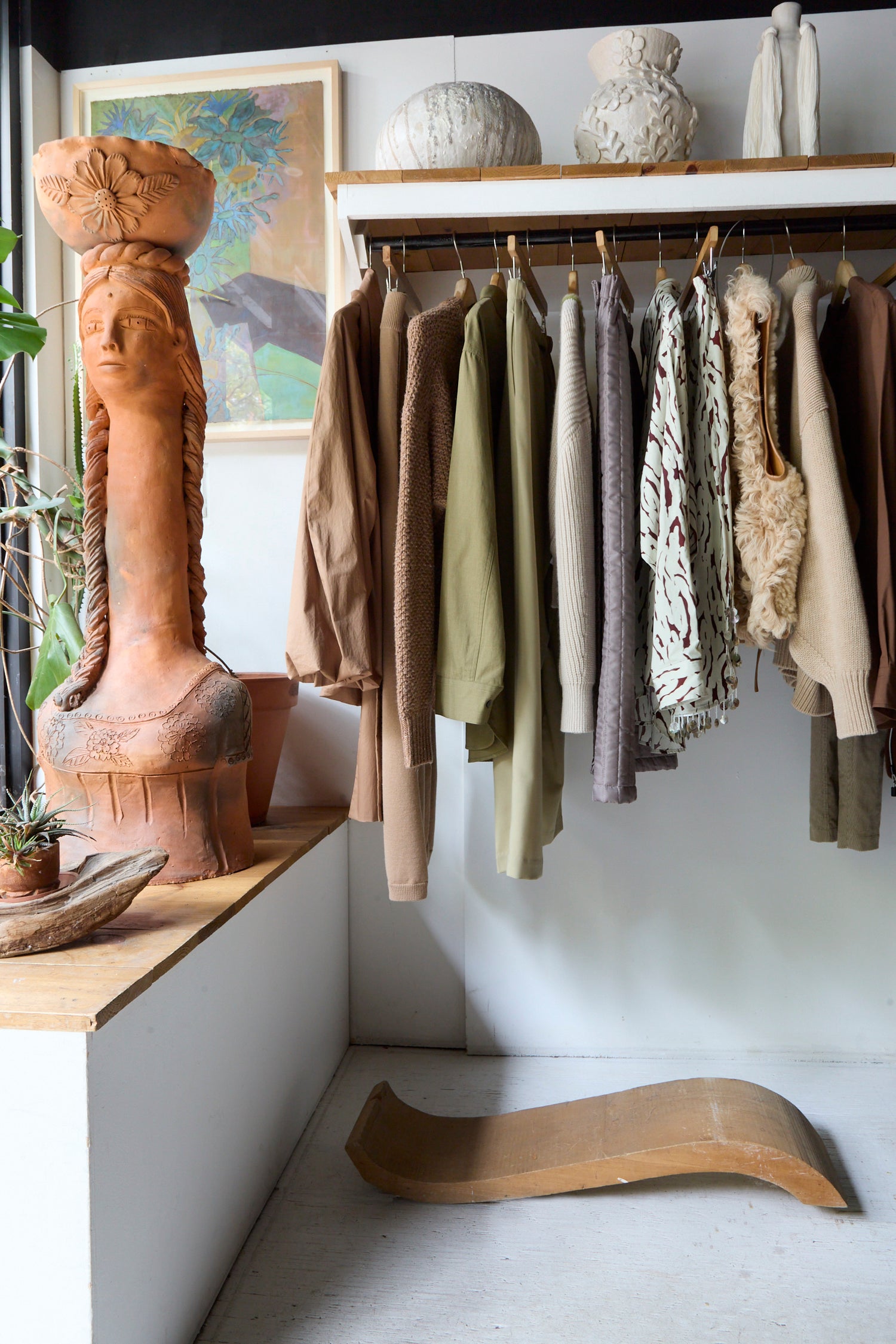 The interior image of Oroboro Store, including a terra cotta sculpture and clothing hanging from the rack.