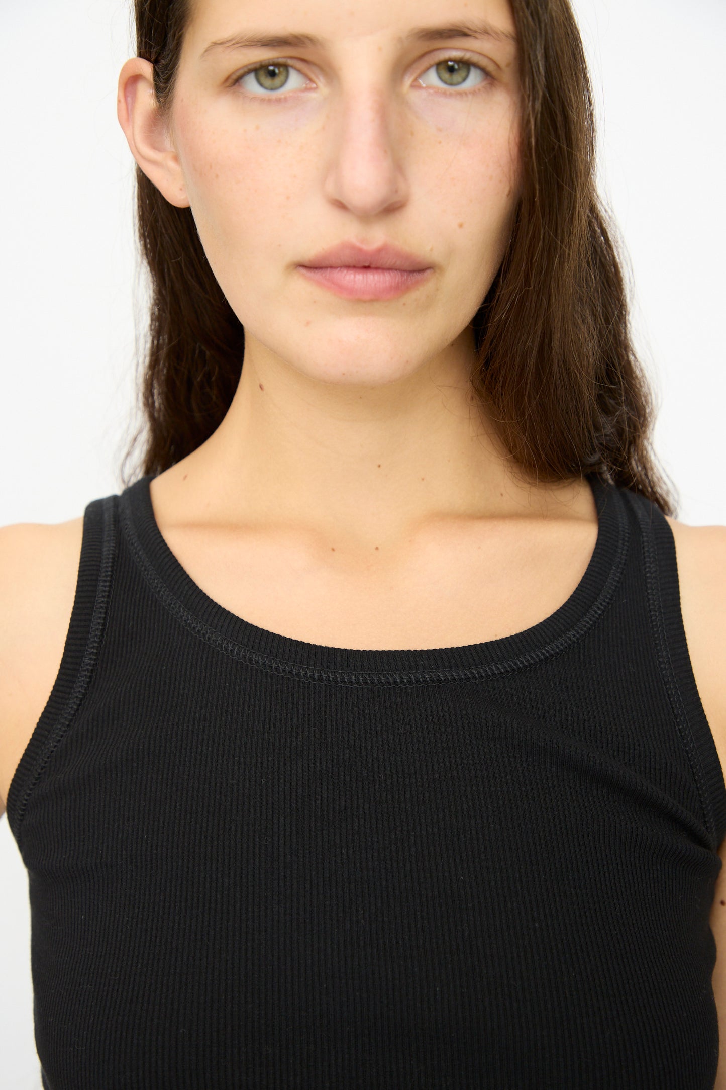 A woman with straight brown hair wears the Ichi Antiquités Cotton Cashmere Tank Top in Black, standing against a plain white background and facing the camera.