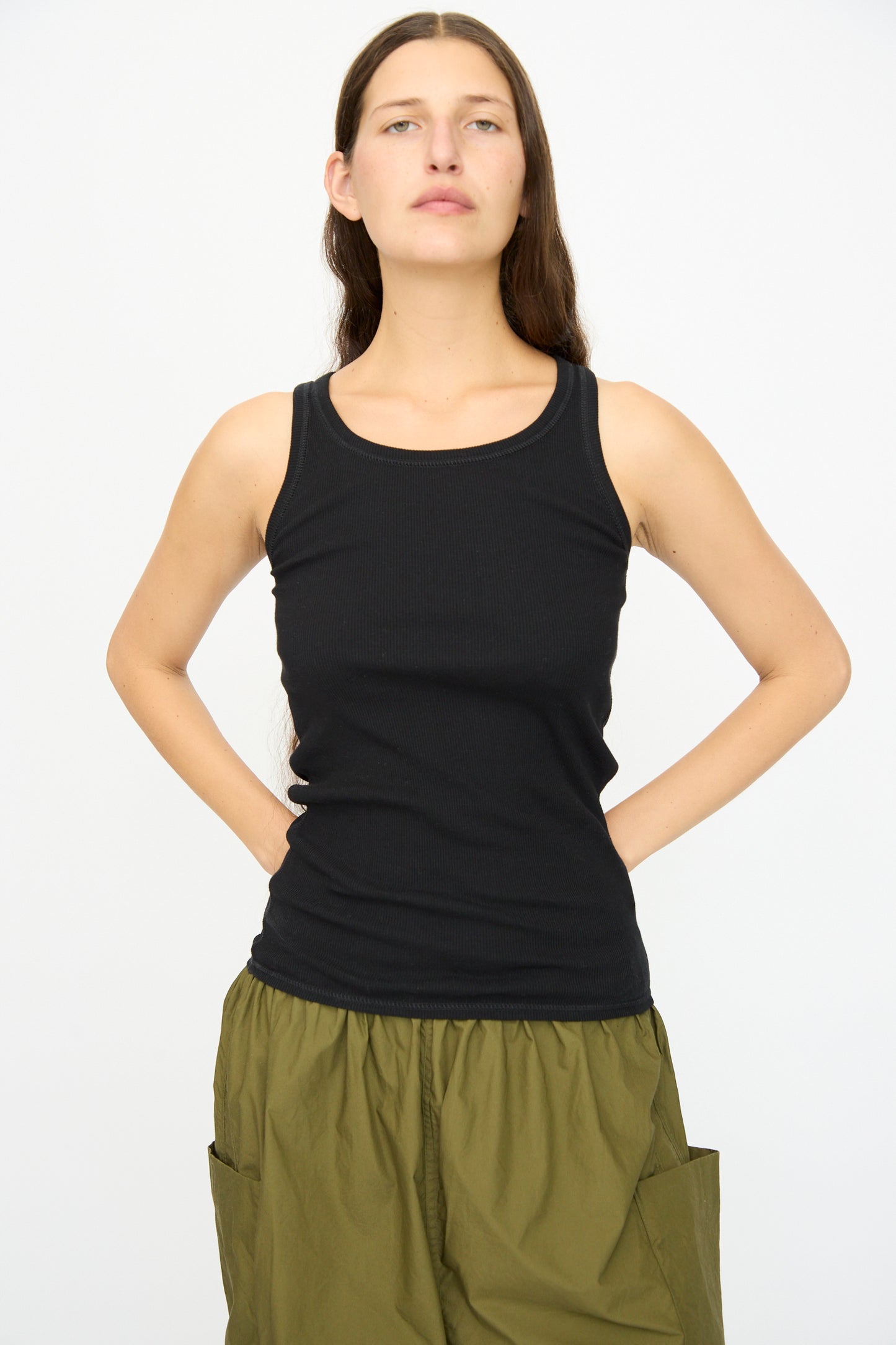 A person faces forward against a plain white background, wearing the Ichi Antiquités Cotton Cashmere Tank Top in Black and olive green pocket pants.