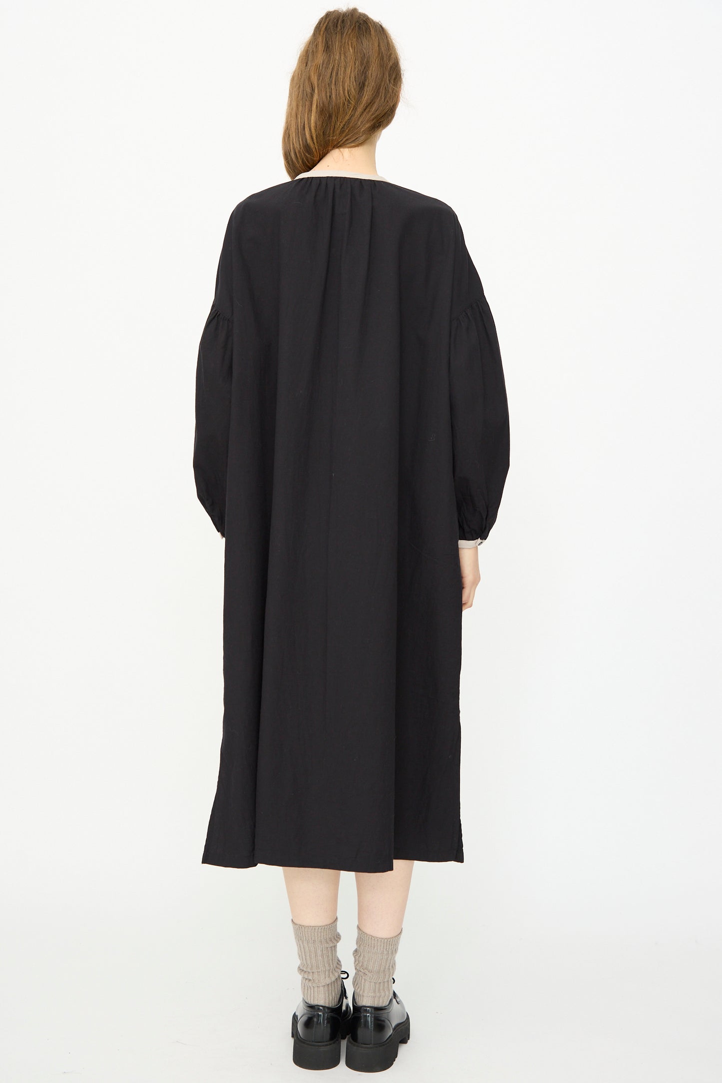 Person shown from the back against a white background, wearing the Ichi Antiquités Cotton Cashmere Viyella Dress in Black, paired with gray socks and black shoes.