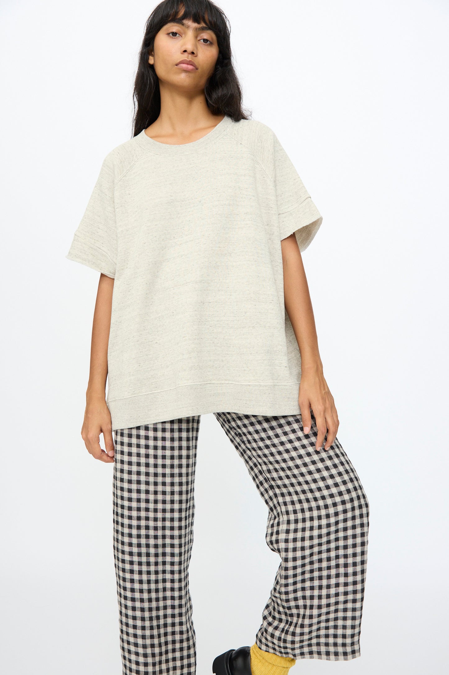 A person wears the Ichi Antiquités Cotton Fleece Pullover in Gray with wide-leg black-and-white checkered pants, made in Japan, standing against a plain white background.