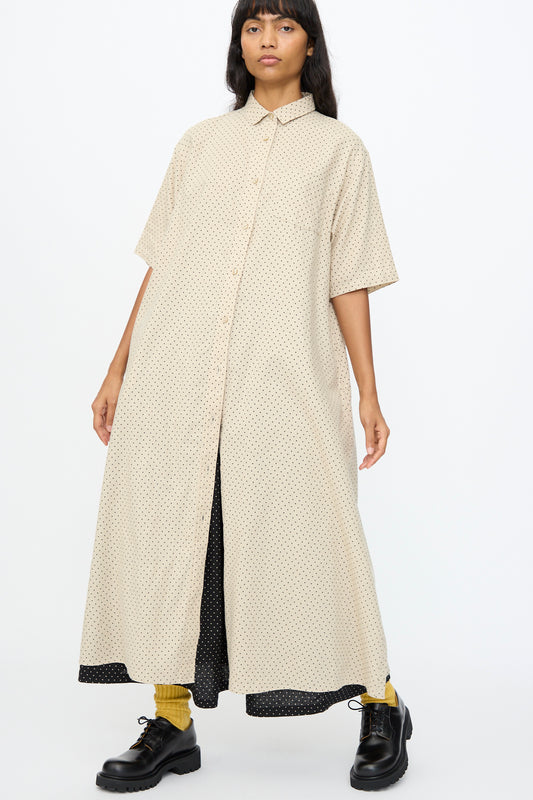 A person wearing the Ichi Antiquités Cotton Linen Dot Dress in Natural stands against a plain white background, paired with yellow socks and black shoes.