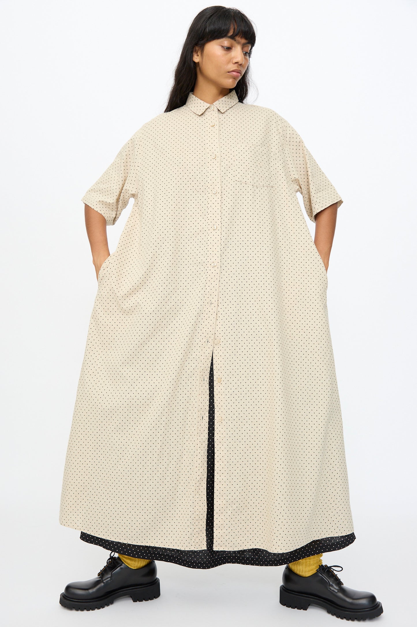 A woman in the Ichi Antiquités Cotton Linen Dot Dress in Natural, featuring short sleeves and an oversized fit, pairs it with yellow socks and black platform shoes, standing against a plain background.