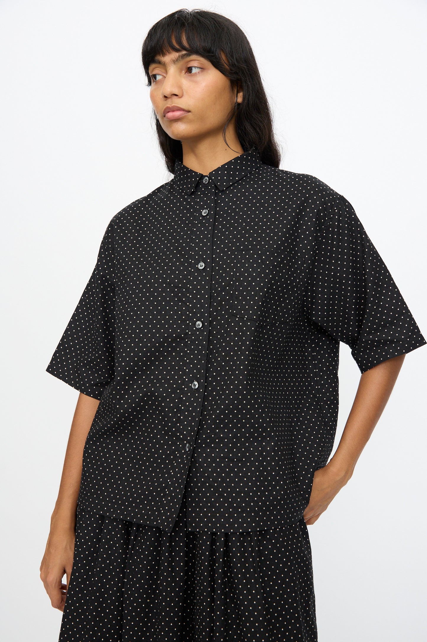 A person wears the Ichi Antiquités Cotton Linen Dot Shirt in Black—an oversized, short-sleeved top—standing against a plain light background.