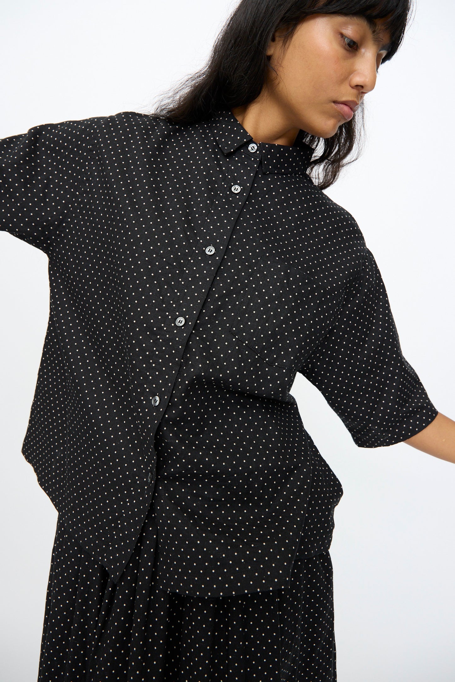 Wearing the Ichi Antiquités Cotton Linen Dot Shirt in Black, featuring a small white pattern, a person stands against a plain background.