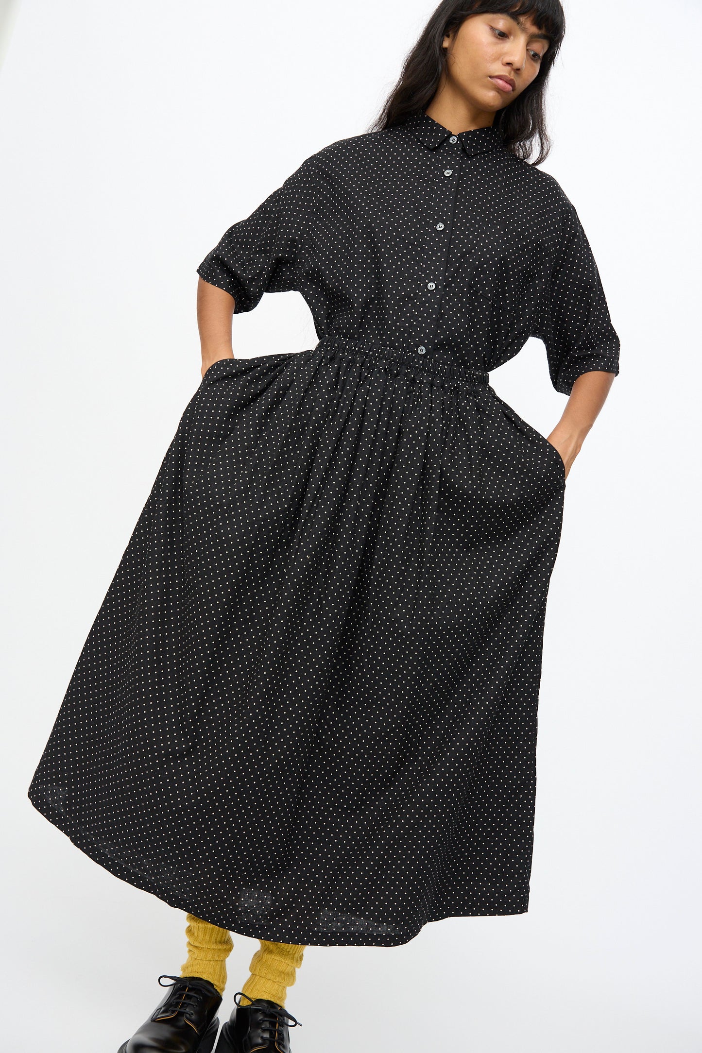 A person wears the Ichi Antiquités Cotton Linen Dot Skirt in Black, styled with yellow socks and black shoes, against a plain background.