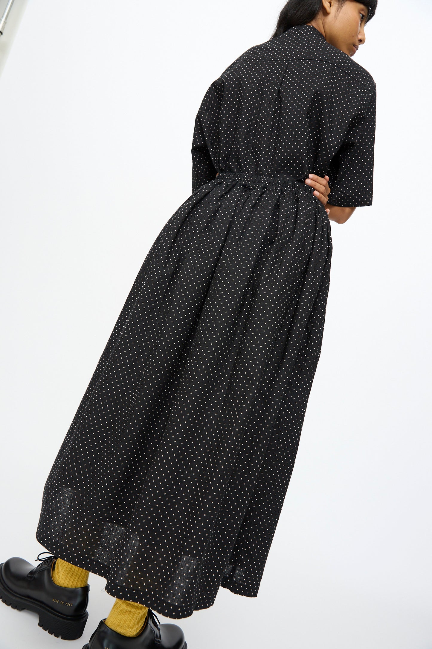 Model wears the Ichi Antiquités Cotton Linen Dot Skirt in Black styled as an ankle-length dress with short sleeves, paired with black platform shoes and yellow socks, standing against a plain white background.