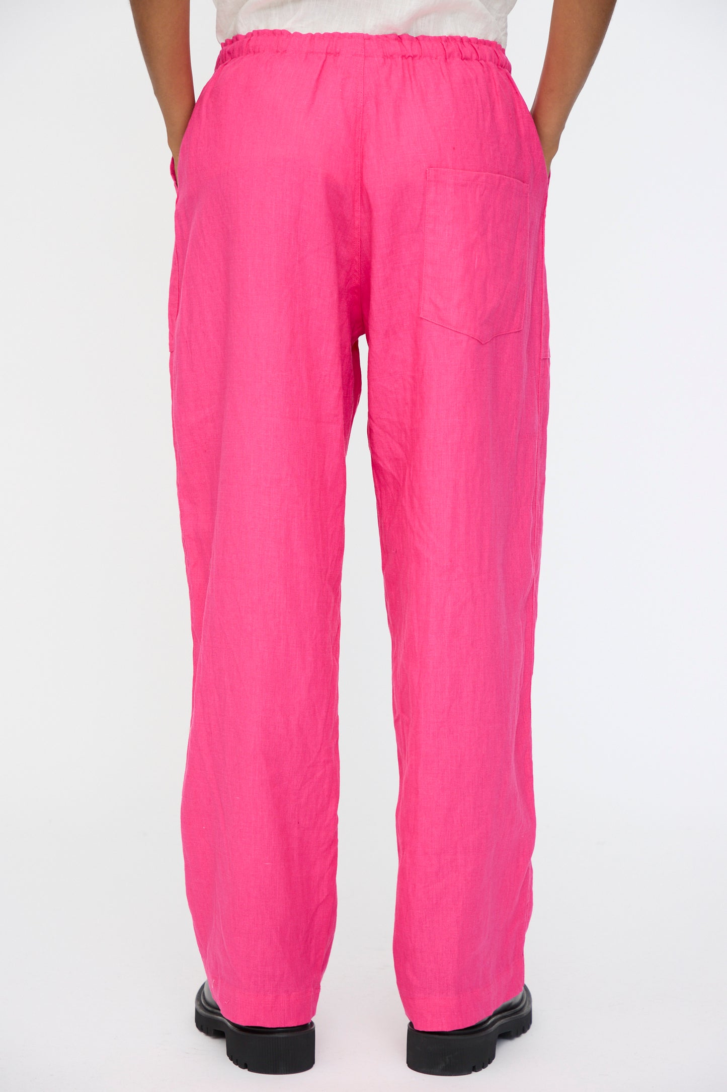 A person wears Ichi Antiquités Color Linen Pants in Pink—relaxed fit, made in Japan with an elastic waistband and single back pocket—standing against a plain white background.