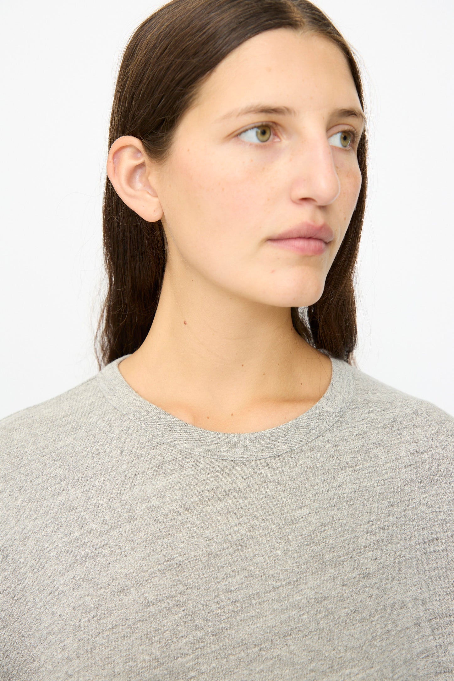 A person with long brown hair wears the Ichi Antiquités Cotton Loose Pullover in Gray, looking slightly to the side against a plain white background.
