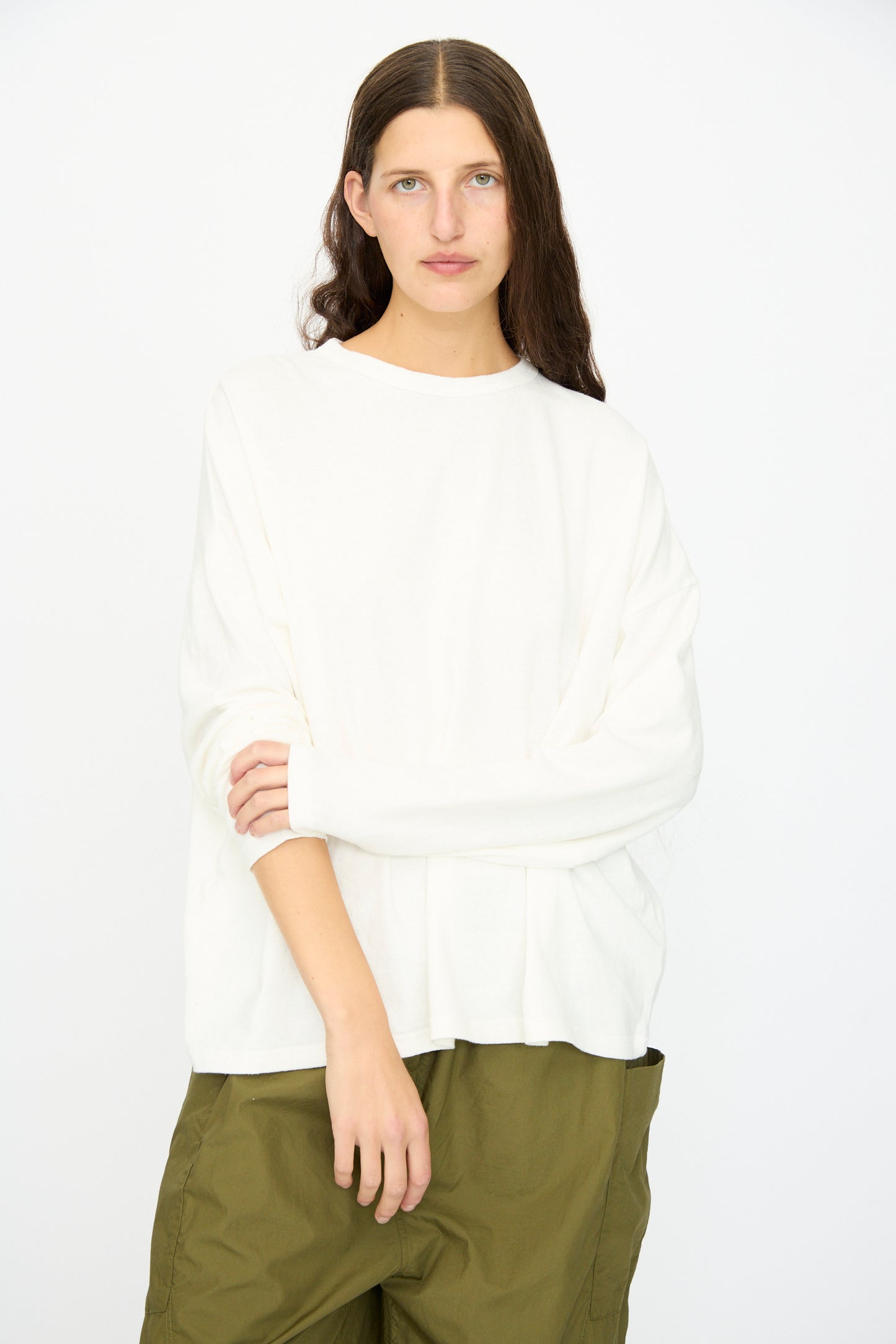 A person with long brown hair wears the Ichi Antiquités Cotton Loose Pullover in White, paired with olive green pants, standing against a plain white background.