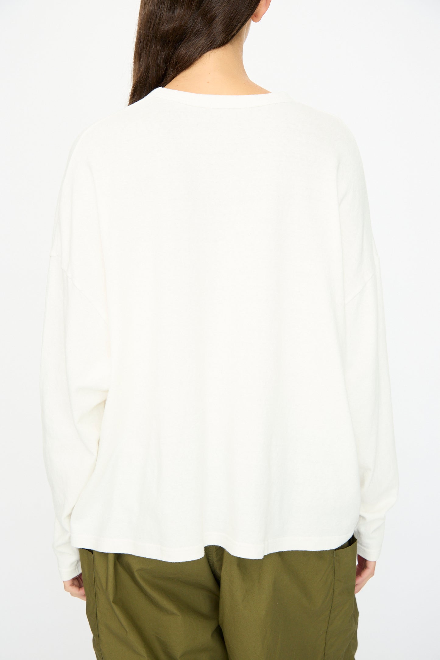A person with long brown hair, seen from behind, wears the Ichi Antiquités Cotton Loose Pullover in White, paired with olive green pants, set against a plain light background.