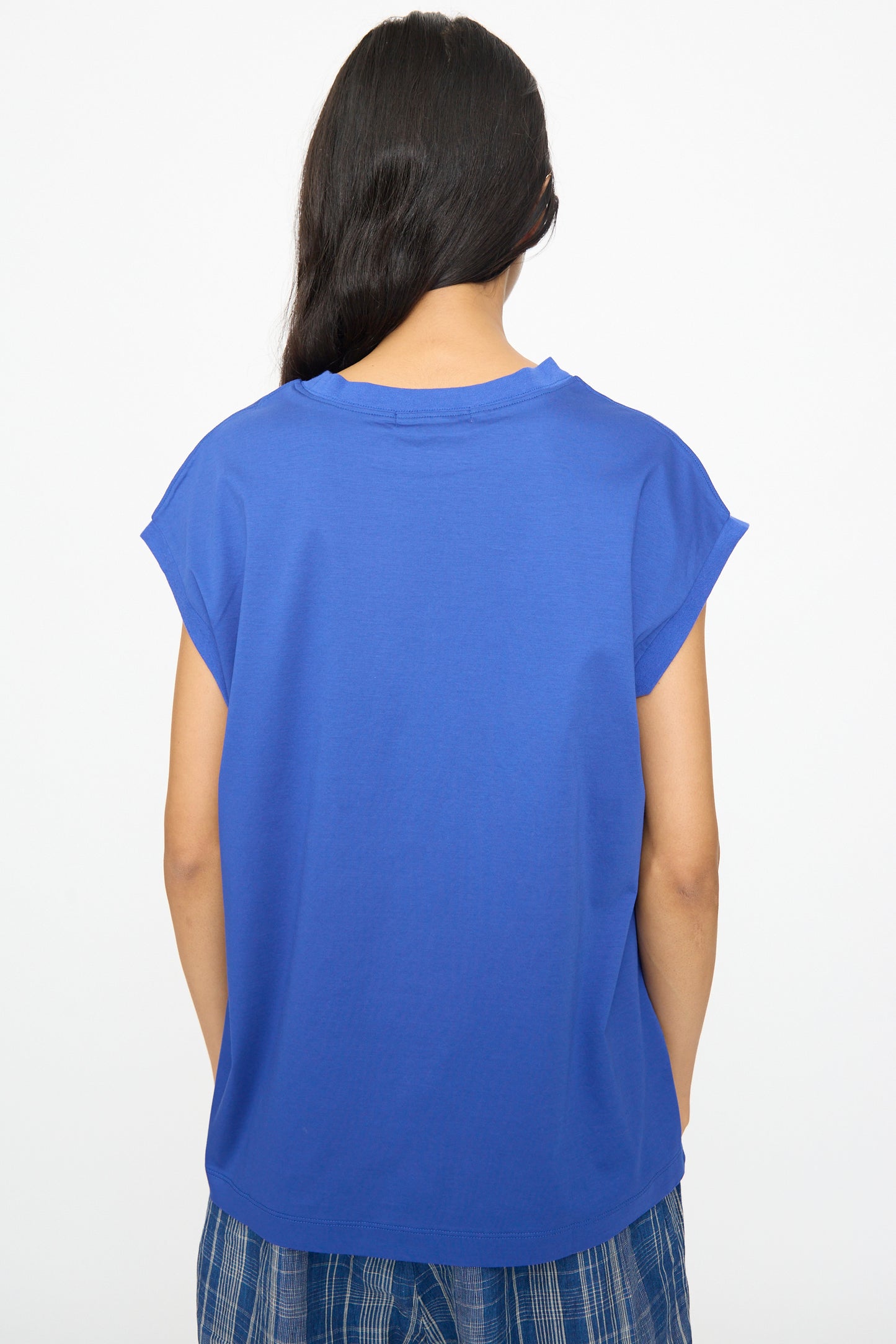 Person with long dark hair is seen from the back wearing the Ichi Antiquités Cotton Sleeveless Pullover in Blue, paired with blue plaid pants, set against a plain white background.