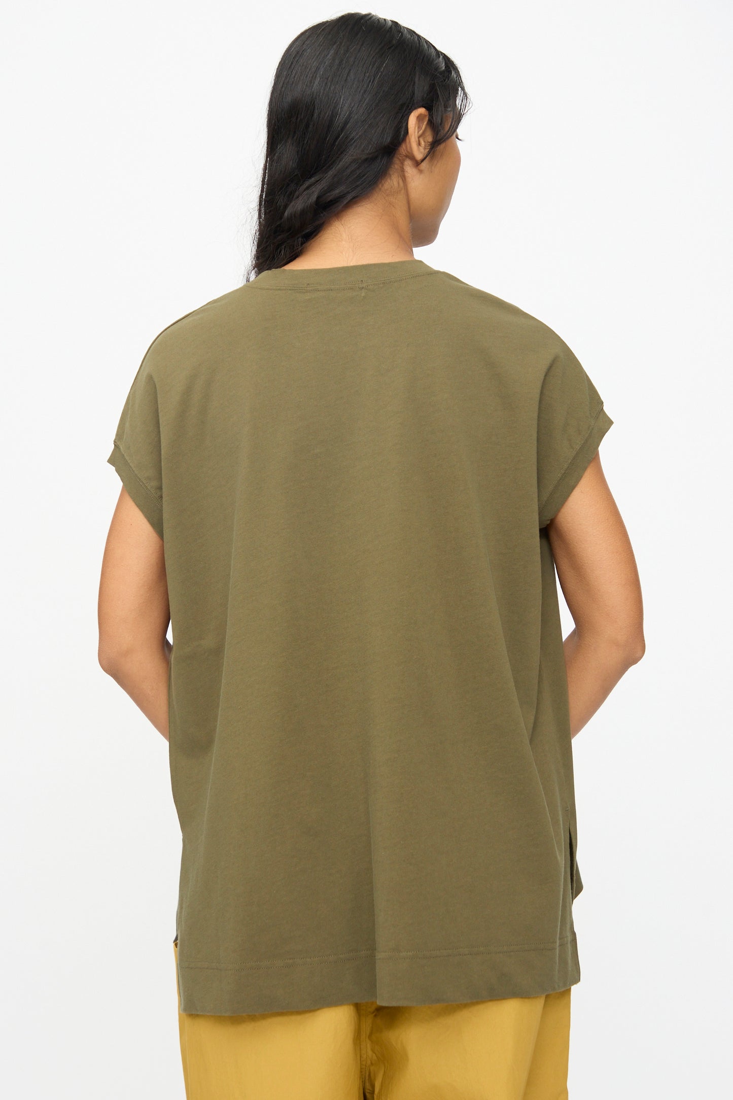 A person stands with their back to the camera, wearing the Ichi Antiquités Cotton Sleeveless Tee in Khaki and mustard yellow pants, set against a plain white background.