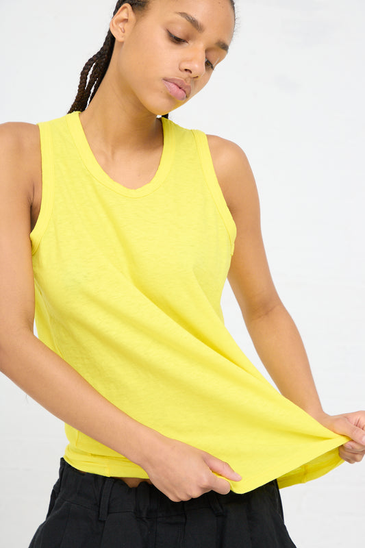 A woman in an Ichi Antiquités lightweight cotton tank in Lemon pulling at the bottom of the shirt.