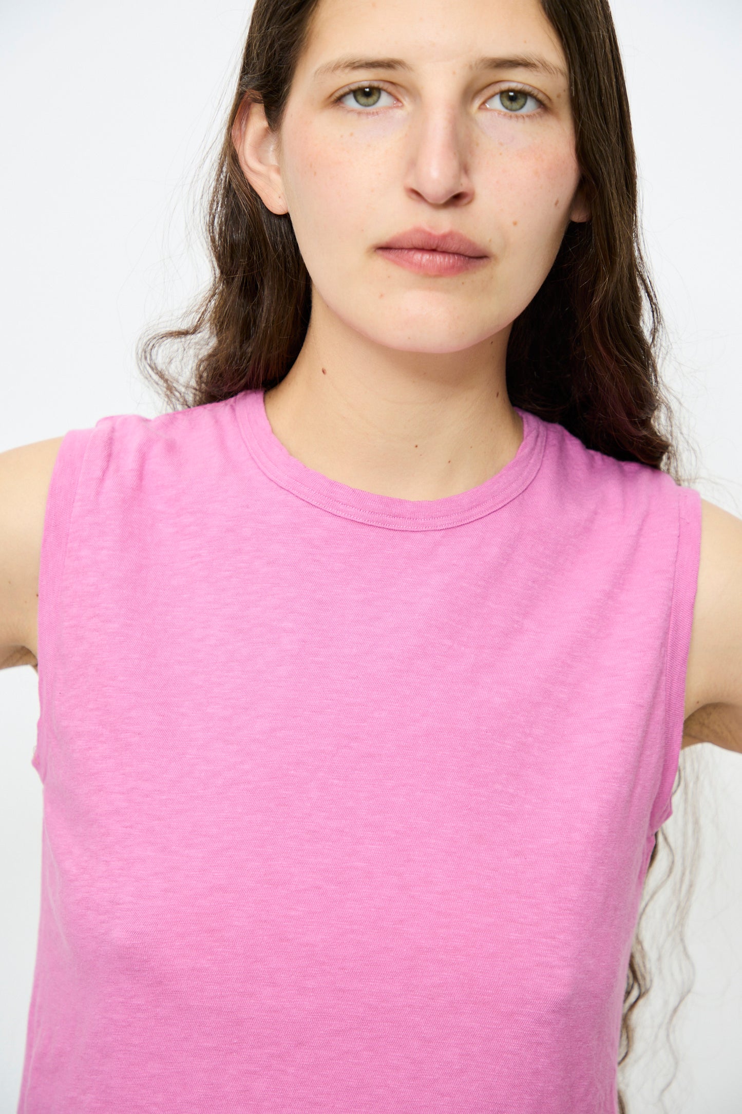 In front of an unadorned backdrop, a long-haired individual wears Ichi Antiquités' Cotton Tank in Pink, a sleeveless top made from lightweight cotton.