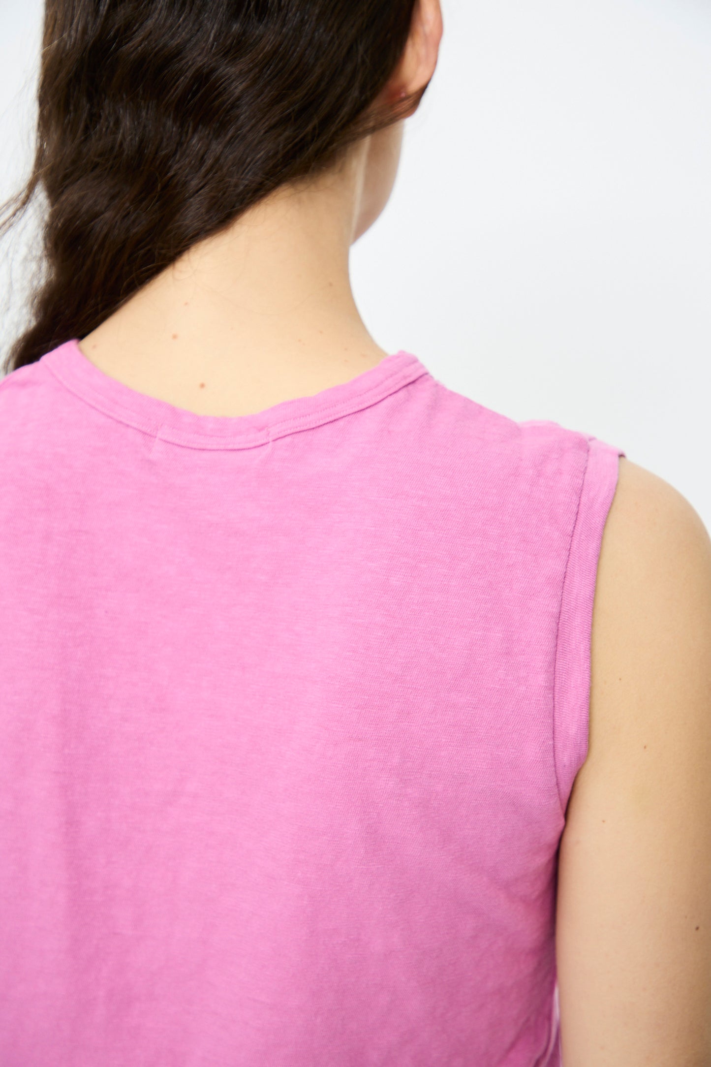 A person with long dark hair in a braid is shown from the back, wearing the sleeveless Cotton Tank in Pink by Ichi Antiquités, made from lightweight cotton and made in Japan.