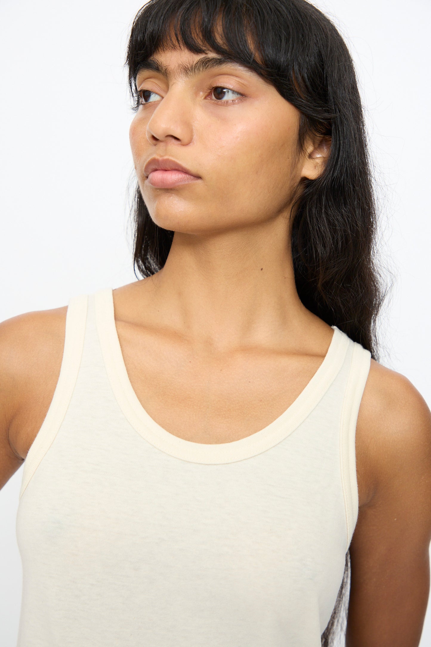 A person with long dark hair wears the Ichi Antiquités Cotton Tank Top in Natural, looking to the side against a plain background.