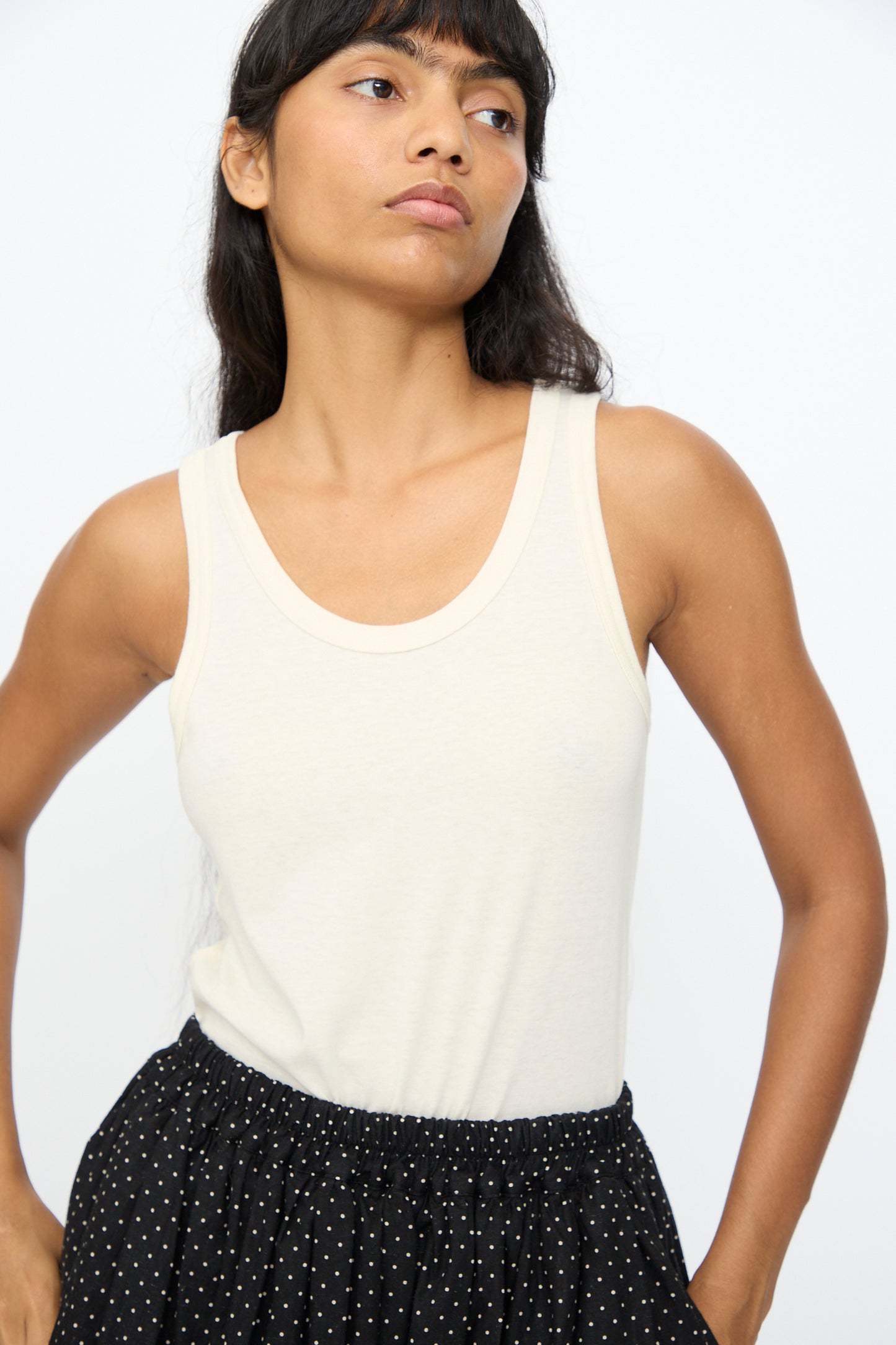 Model wears the Ichi Antiquités Cotton Tank Top in Natural, styled with a black polka dot skirt, standing against a plain white background.