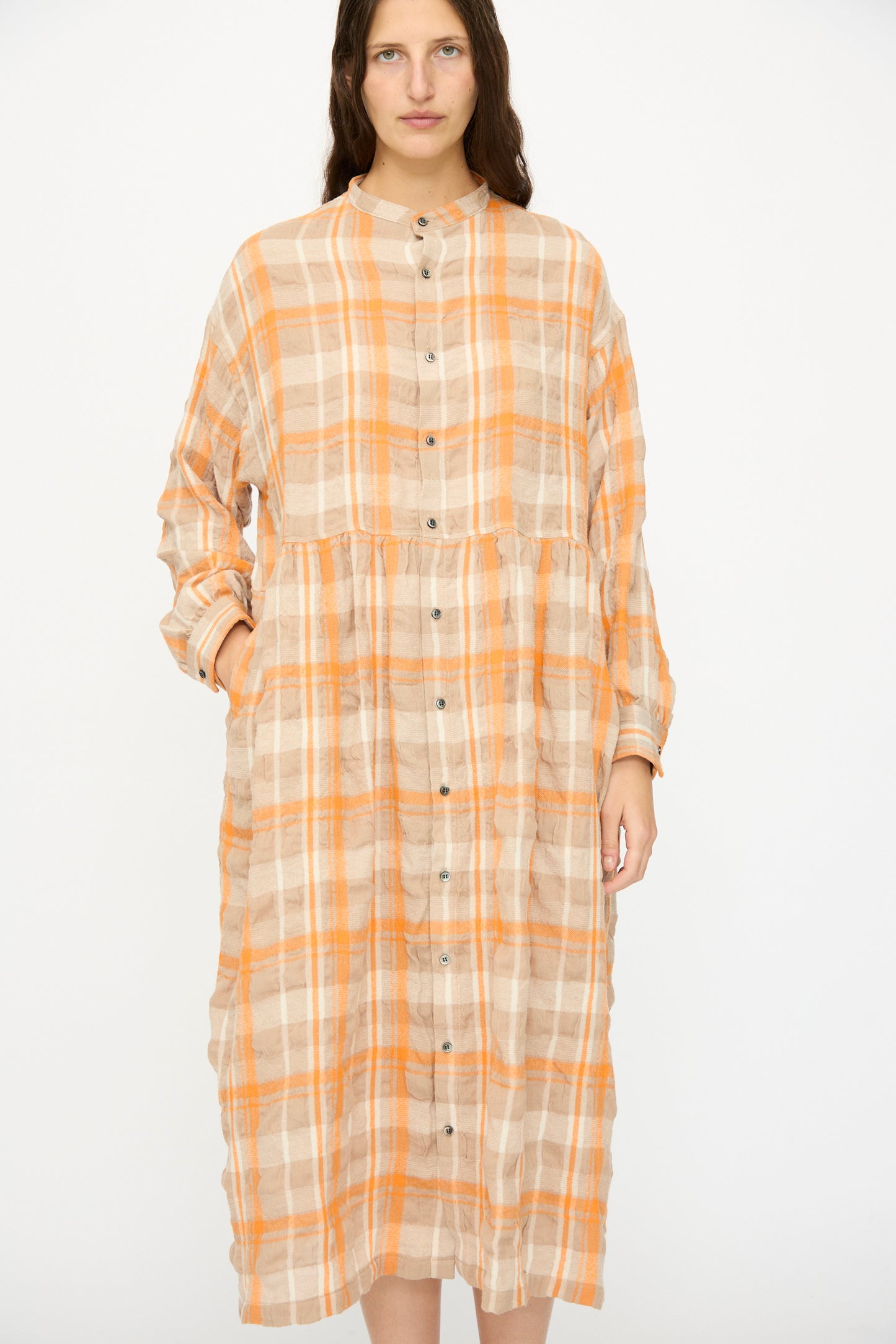 A person wears the Ichi Antiquités Cotton Wool Tartan Check Dress in Orange, featuring a loose, long-sleeve, oversized silhouette with an orange and beige plaid, standing against a plain white background.