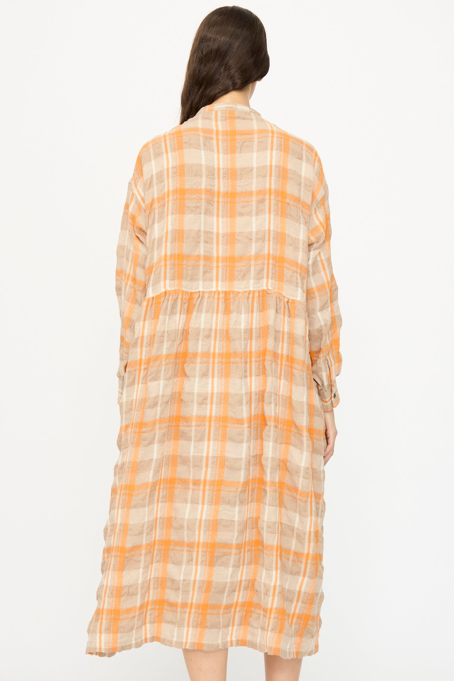 A person with long brown hair is shown from the back wearing the Ichi Antiquités Cotton Wool Tartan Check Dress in Orange, which features a loose, oversized silhouette, against a plain white background.