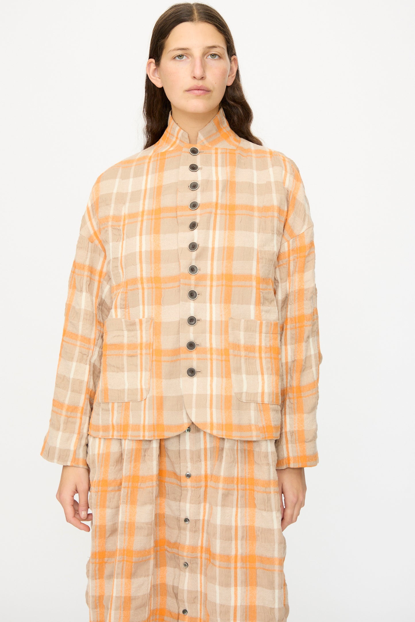 A woman wears the Ichi Antiquités Cotton Wool Tartan Check Jacket in Orange, paired with a matching skirt, standing against a plain white background.