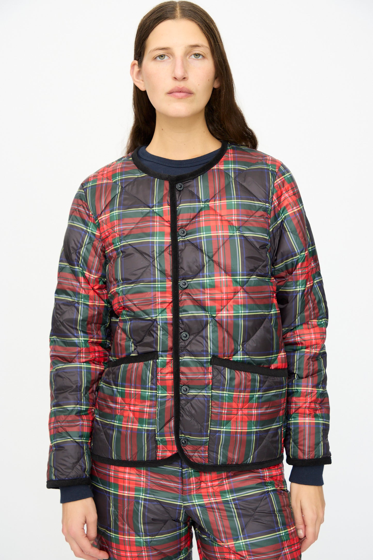 A person wearing the Down Jacket in Black Tartan by Ichi Antiquités, featuring quilted tartan and black corduroy trim, stands against a plain white background.