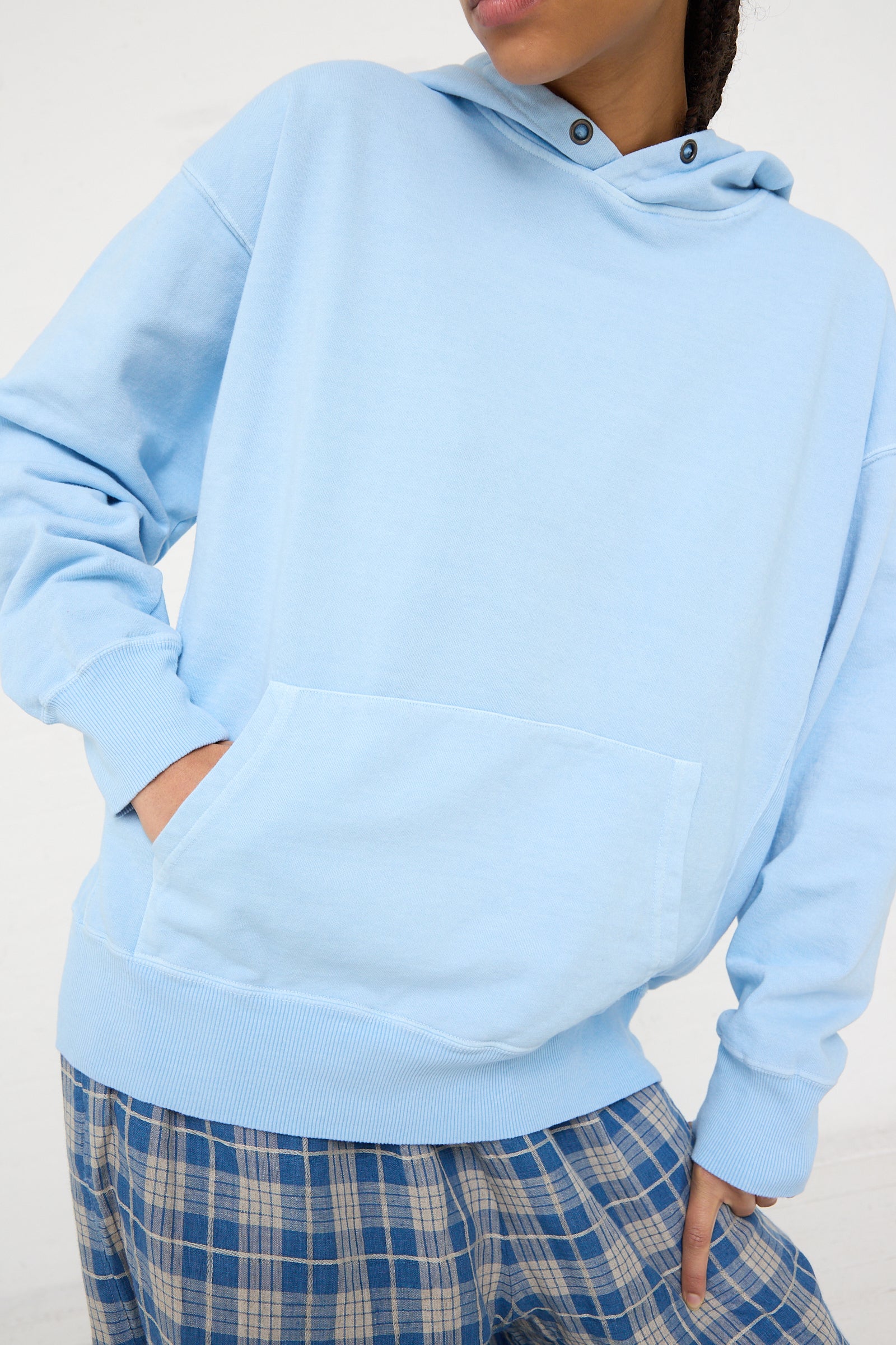 A person wearing an oversized Ichi Antiquités French Terry Hoodie in Blue with a front pocket and plaid trousers.