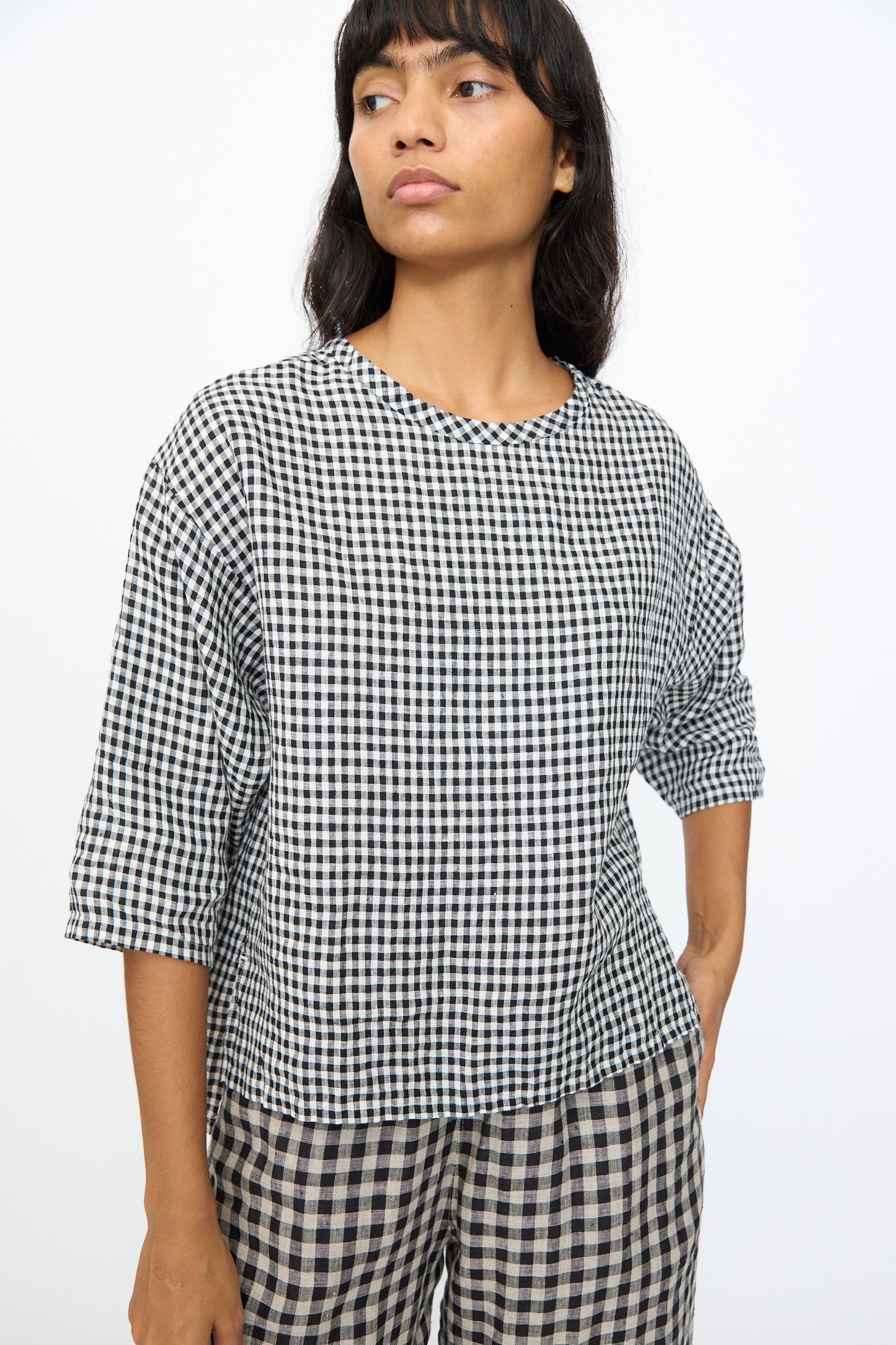 A person wears the Ichi Antiquités Gingham Check Blouse in White and Black, styled with matching checkered pants, standing against a plain white background.