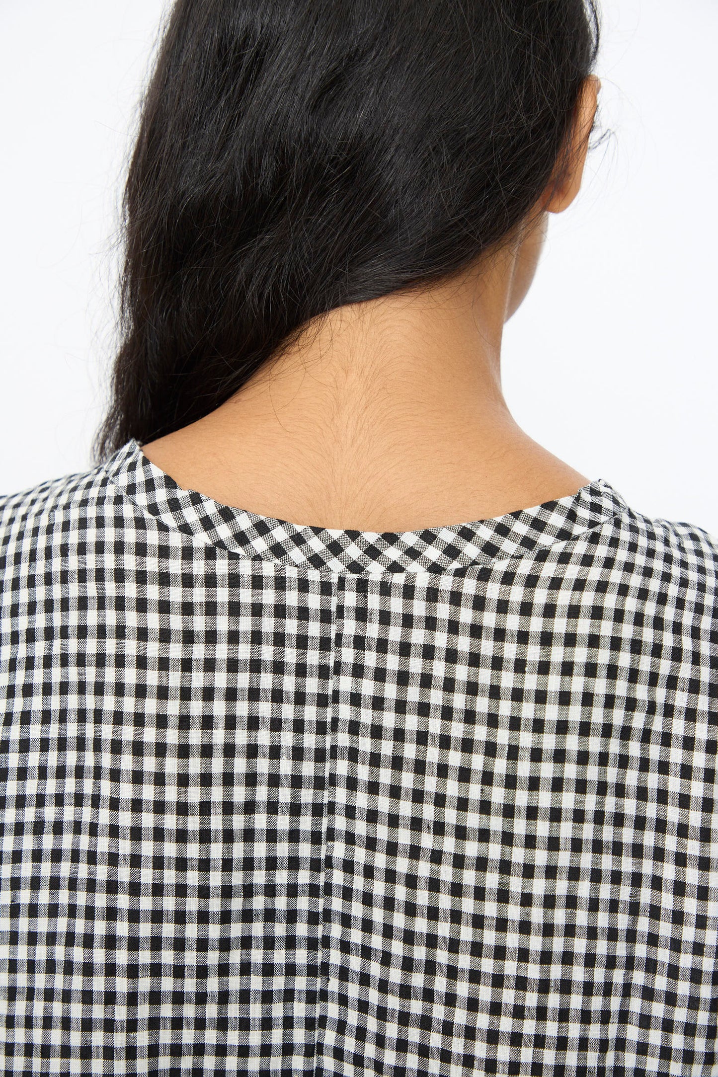 A person with long dark hair is seen from behind wearing the Ichi Antiquités Gingham Check Blouse in White and Black, styled in an oversized fit, against a plain white background.